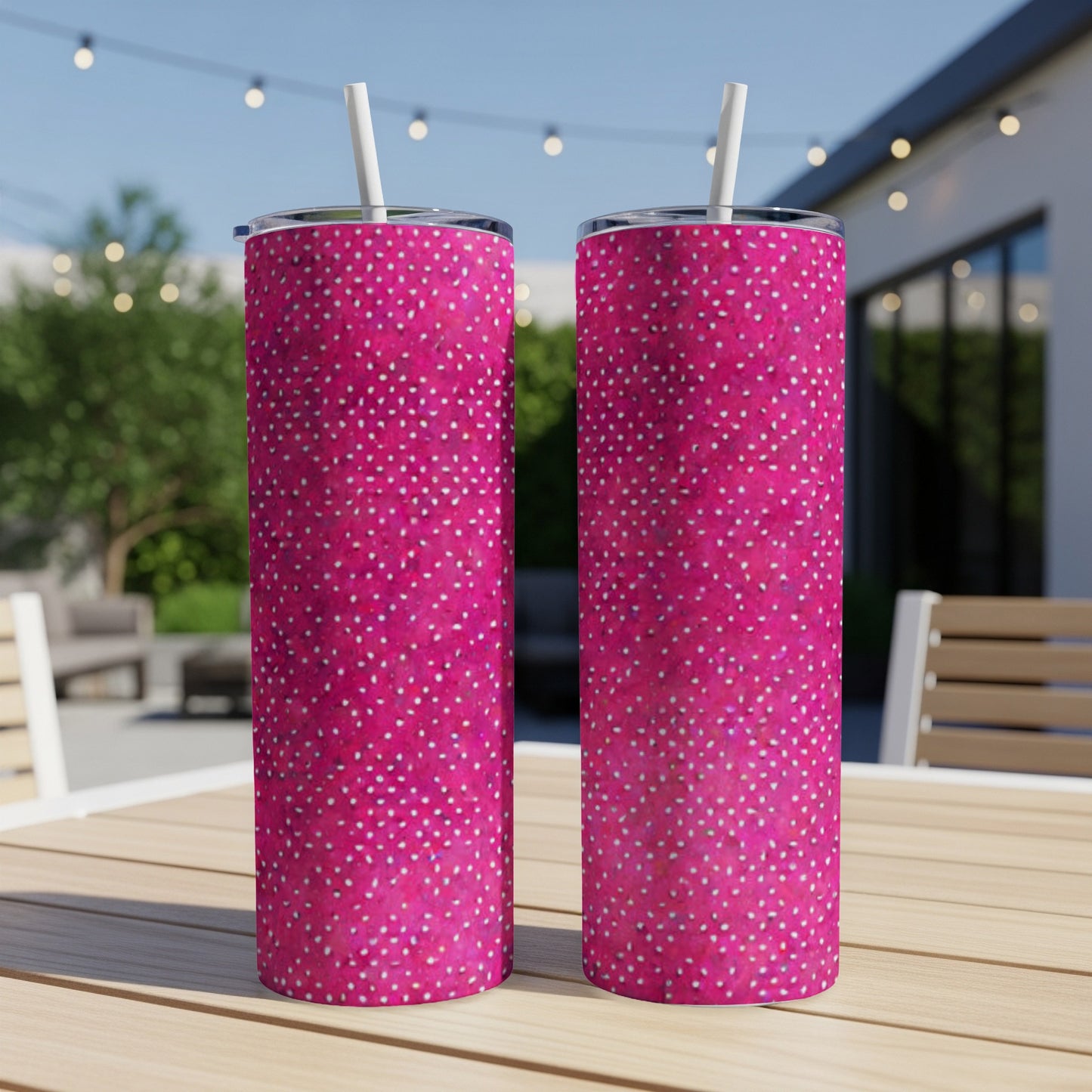 Two pink tumblers with white polka dots and straws on a table.