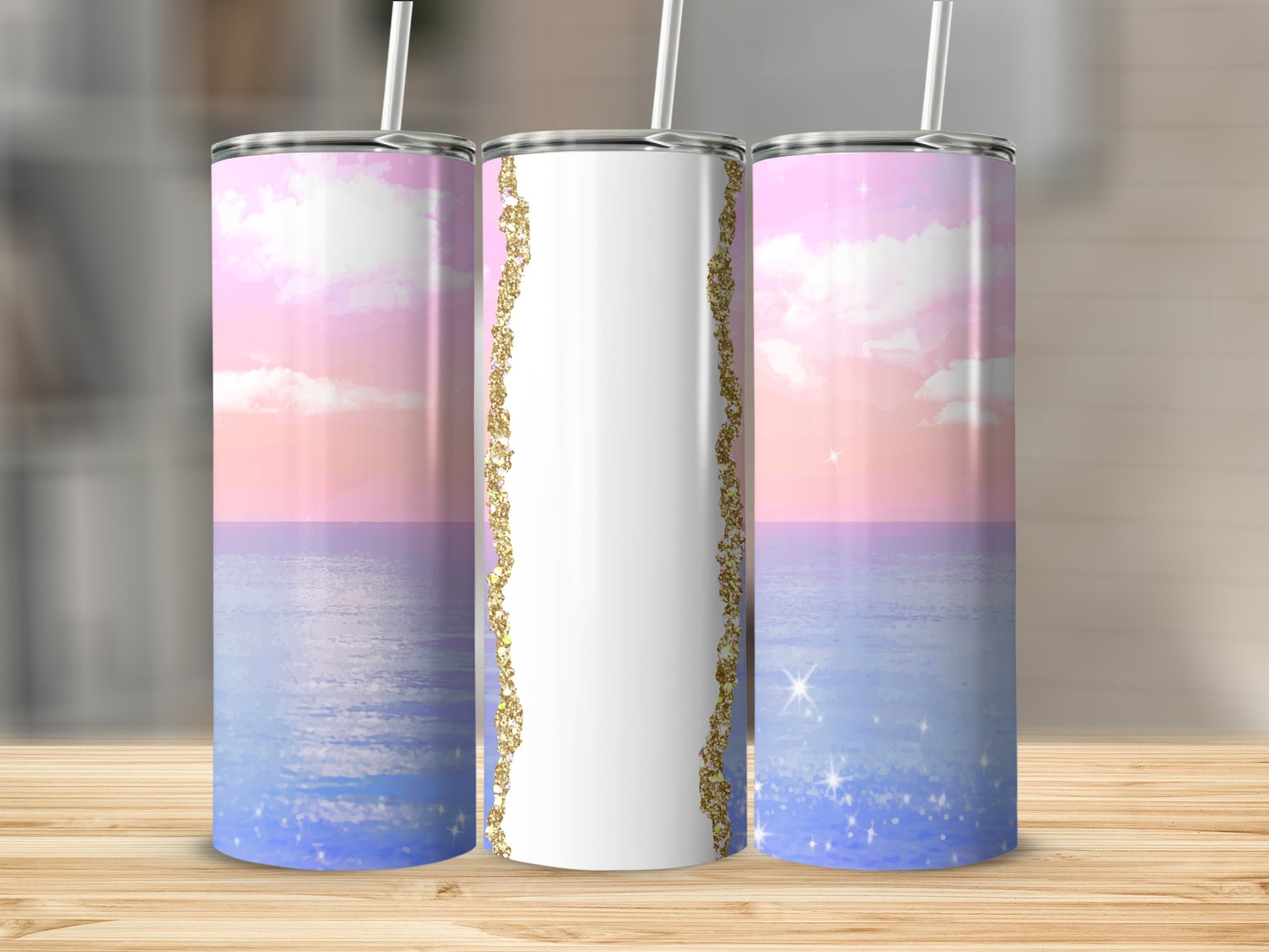 White tumbler with sparkling gold trim and pastel sky and ocean scene.