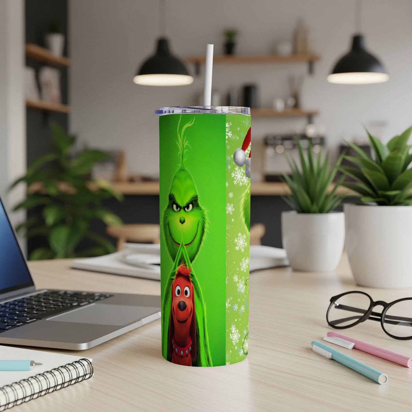Green Grinch tumbler with Max the dog and snowflakes on a desk.