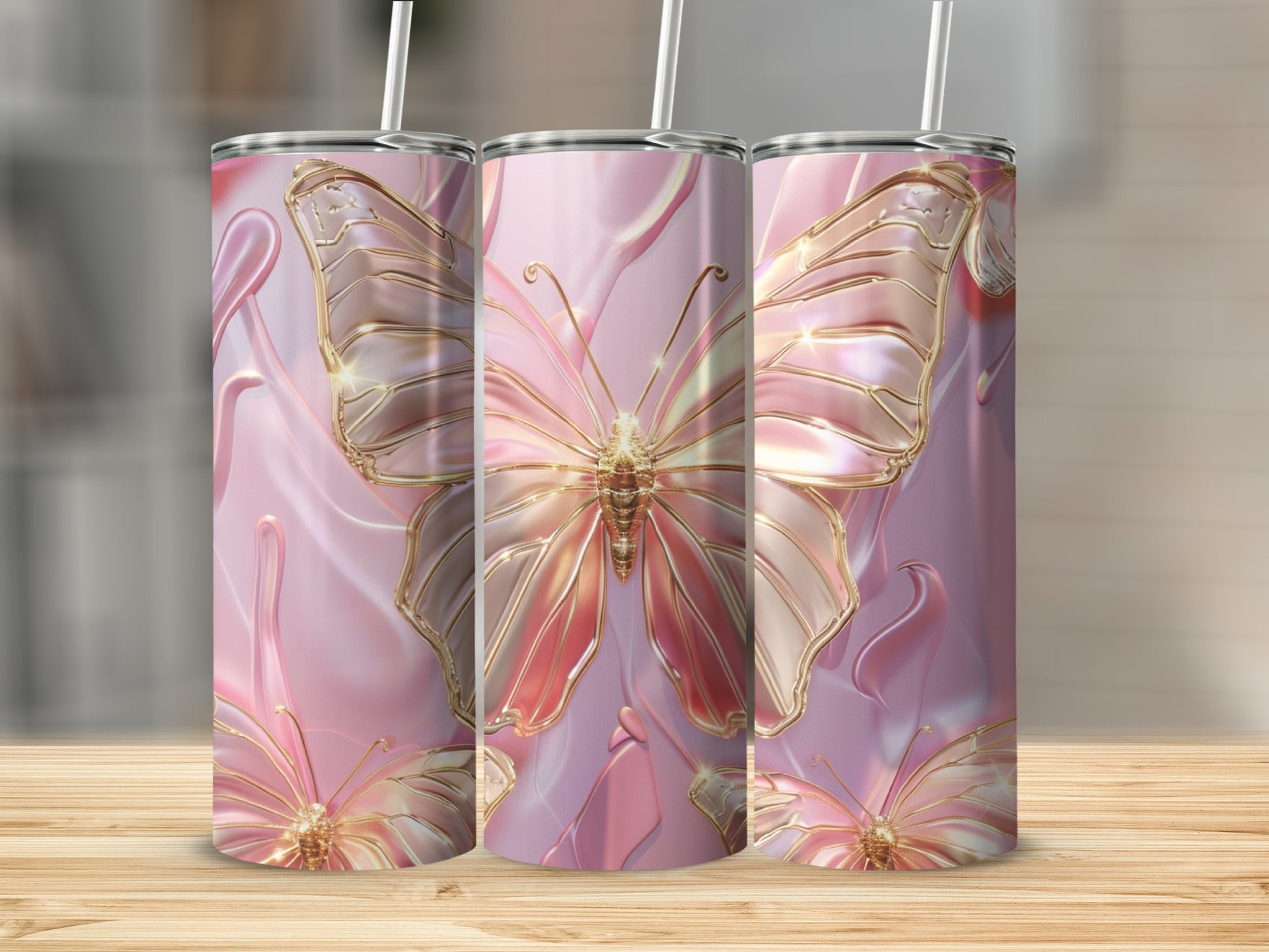 Three pink iridescent tumblers with golden butterfly designs on a wooden surface.