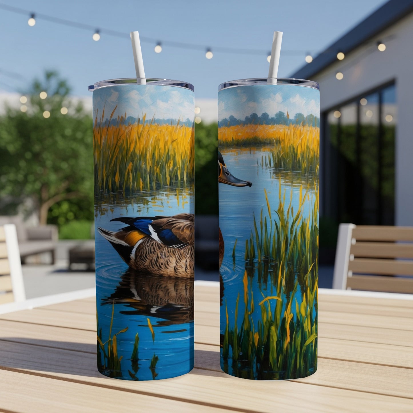 Two tumblers with ducks and reeds on a table outdoors.