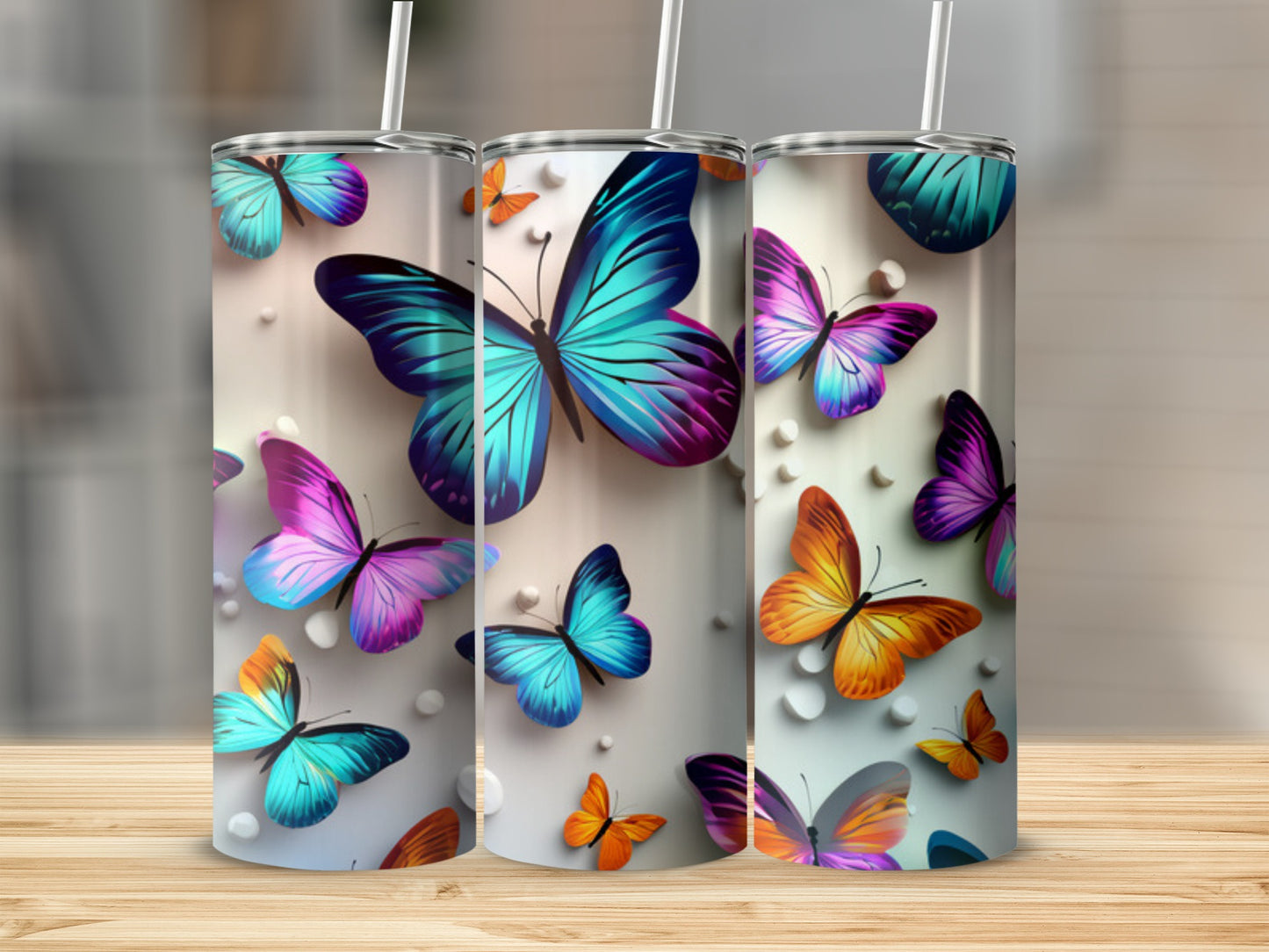 Three tumblers adorned with colorful butterflies on a wooden surface.