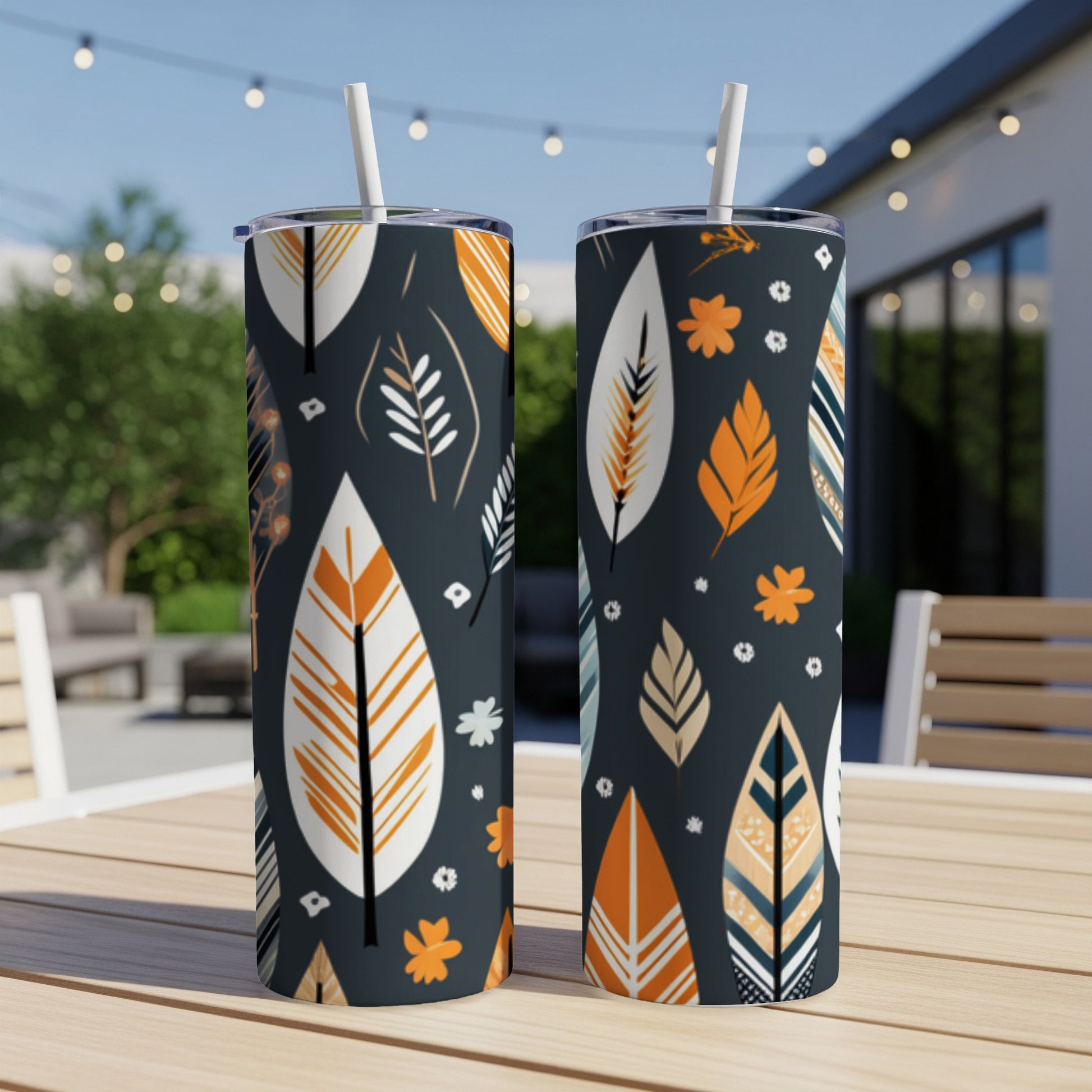 Two tall tumblers with a dark background and a repeating pattern of stylized feathers and small flowers.