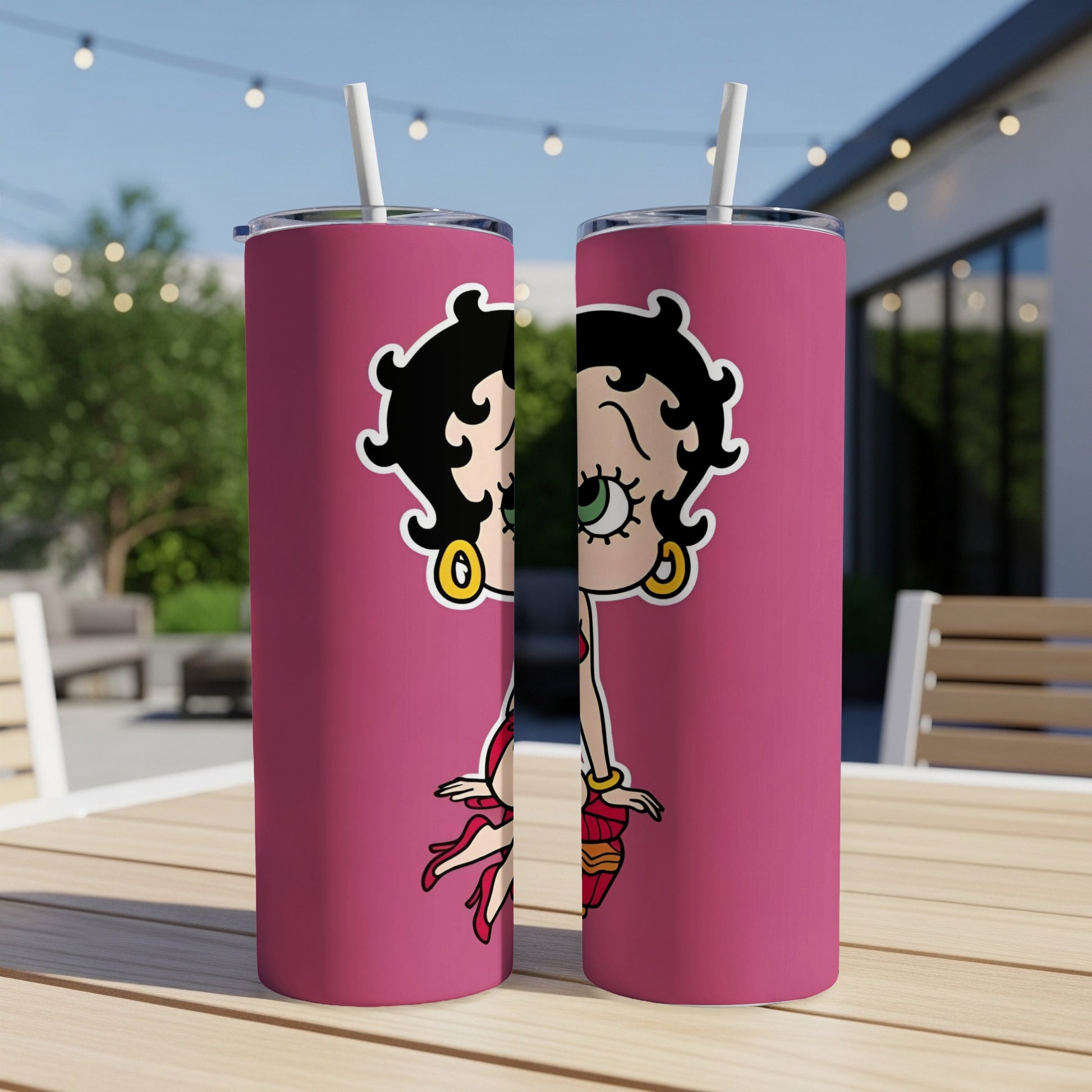 Two Betty Boop tumblers with straws on a table.