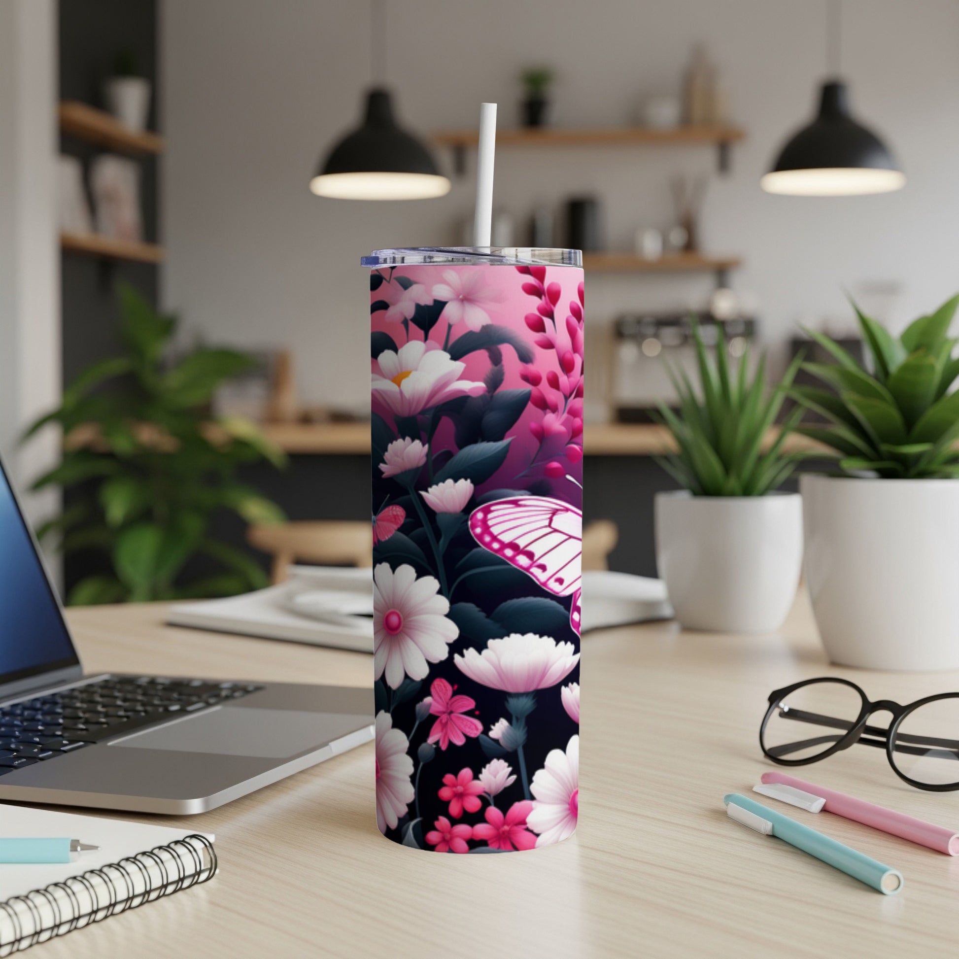 Pink floral pattern tumbler with white butterfly and straw on desk.
