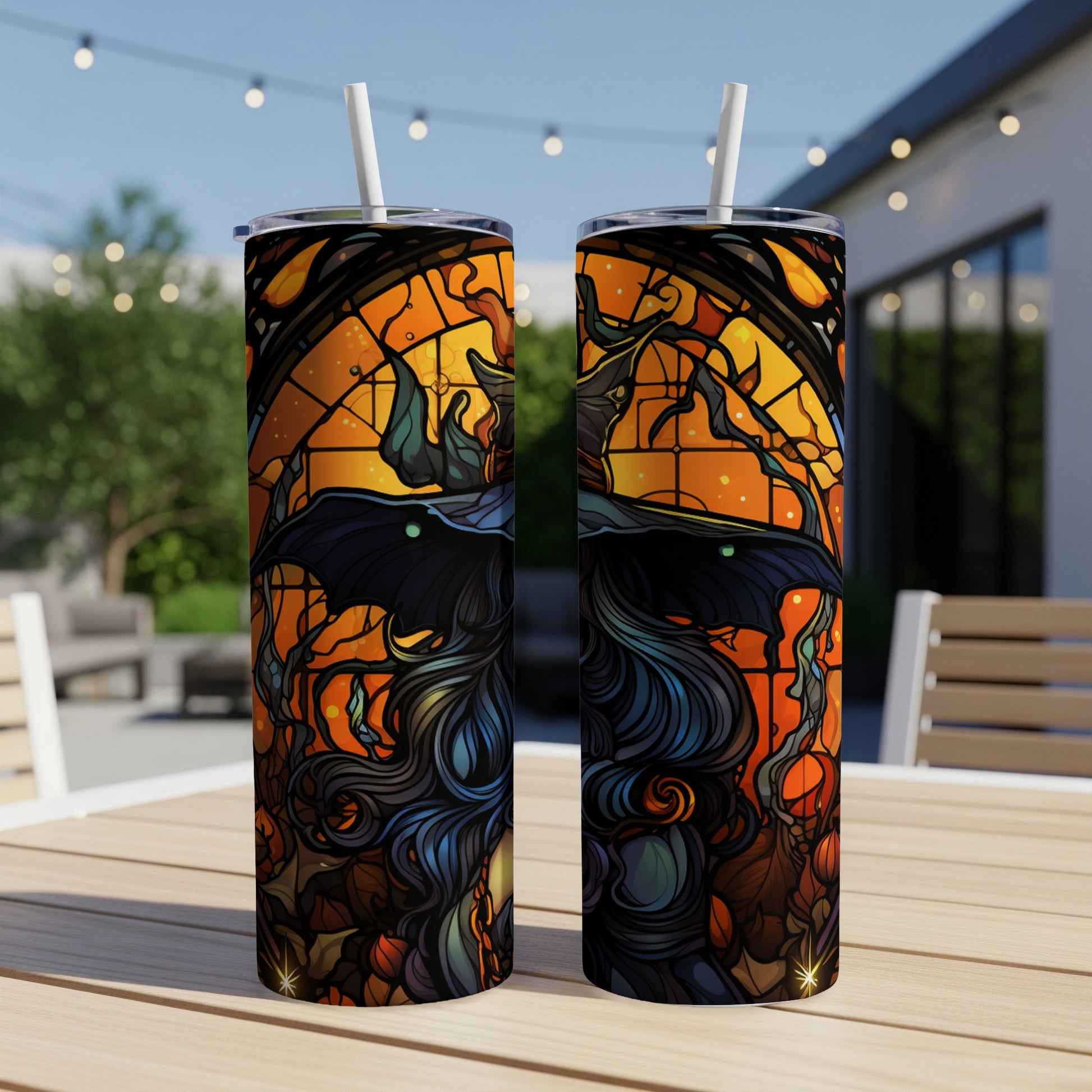 Two tall tumblers with witch and stained glass design on an outdoor table.