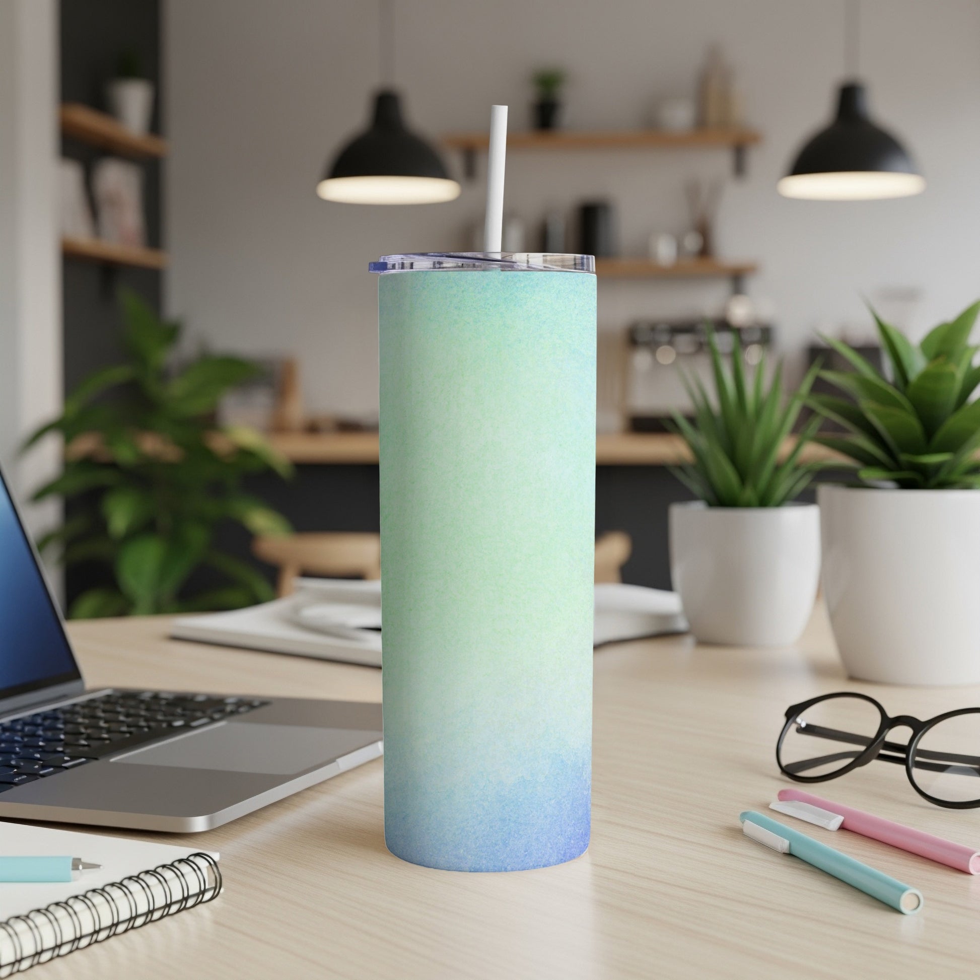 Blue and green gradient 20 oz tumbler with straw on a desk.