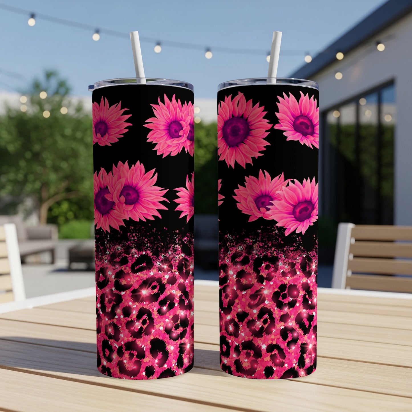 Two pink floral tumblers with leopard print on a table outdoors.
