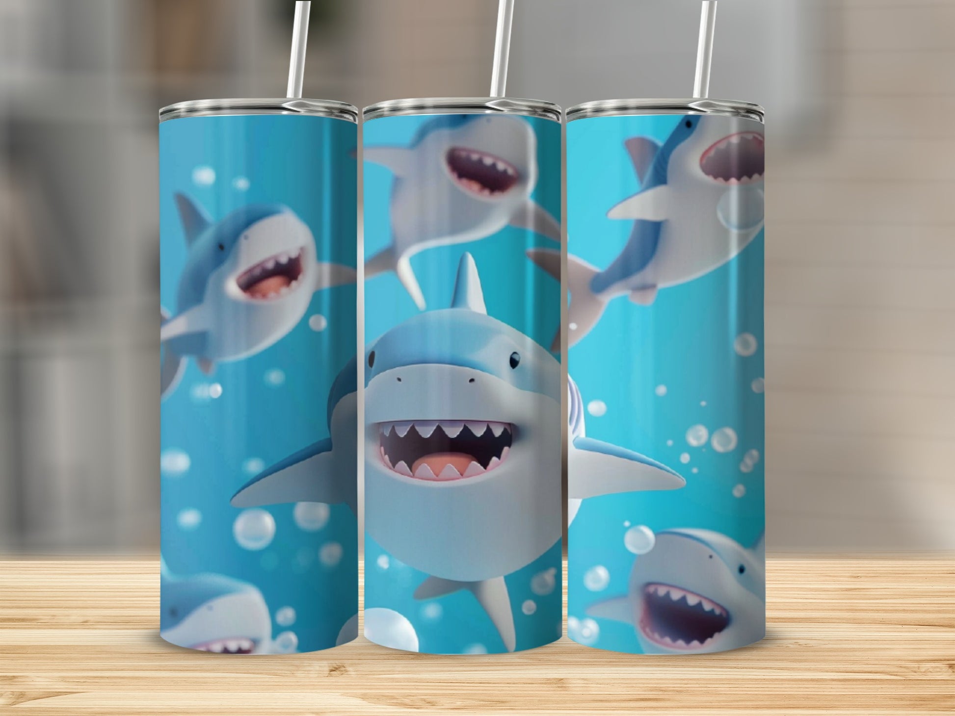Three cartoon shark tumblers with straws on a wooden surface.