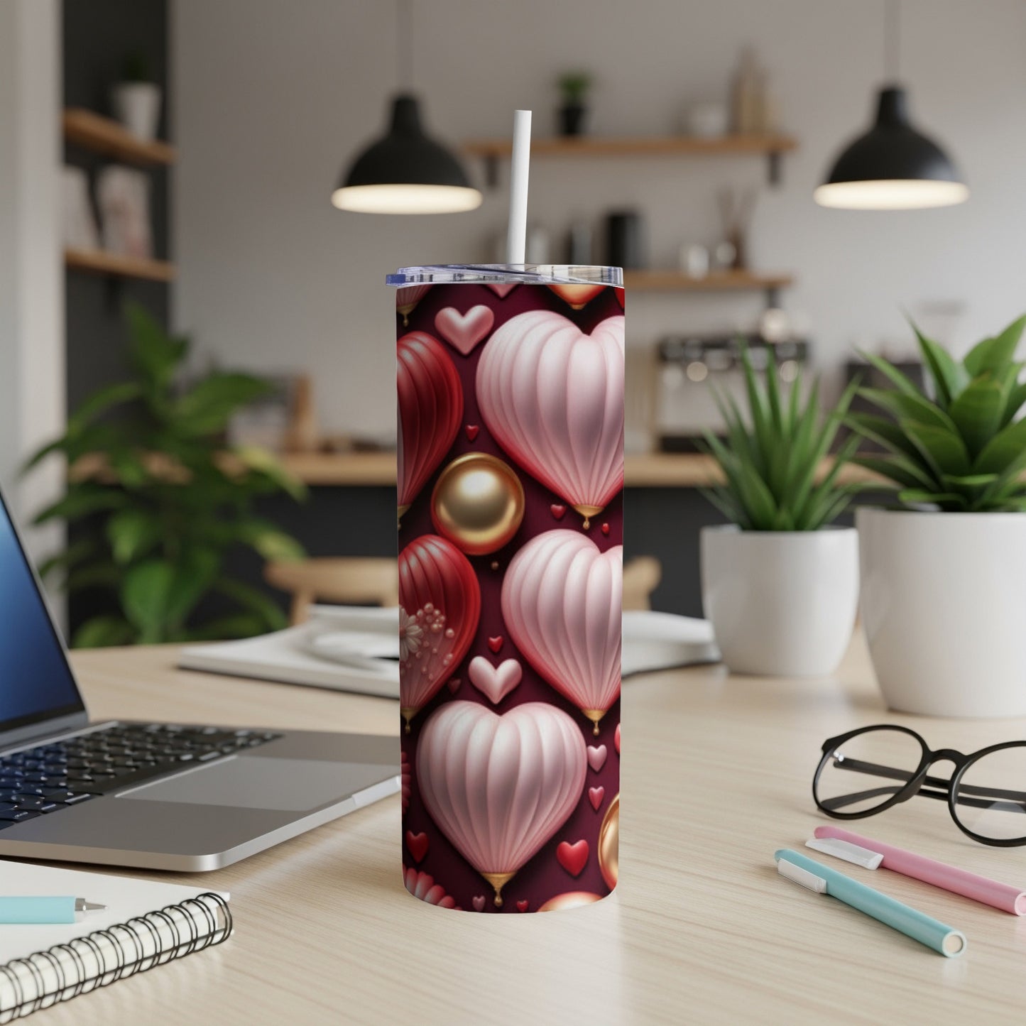 Red and pink heart-patterned tumbler with straw on a desk.