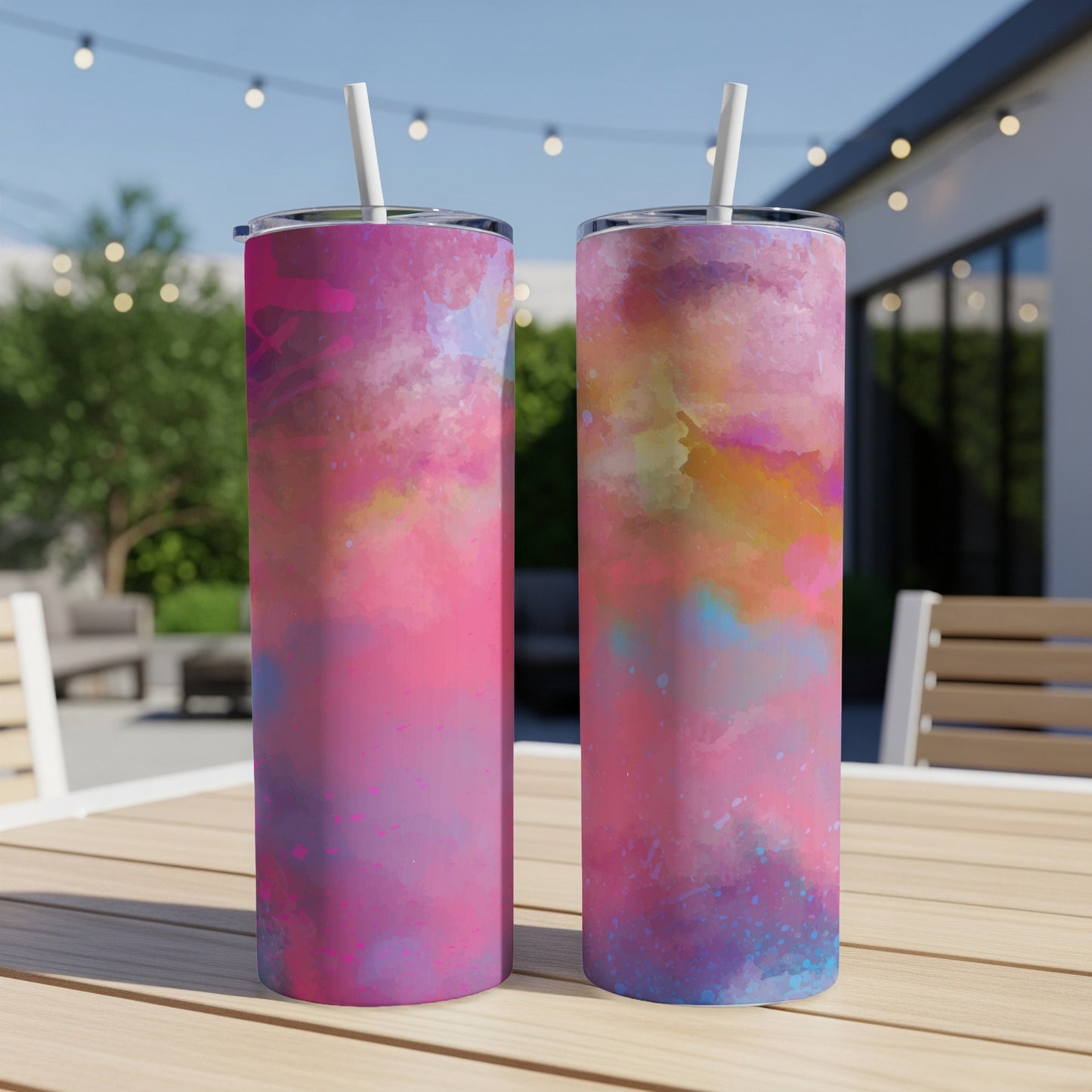 Two tumblers with pink, purple, and blue watercolor abstract designs with white straws.