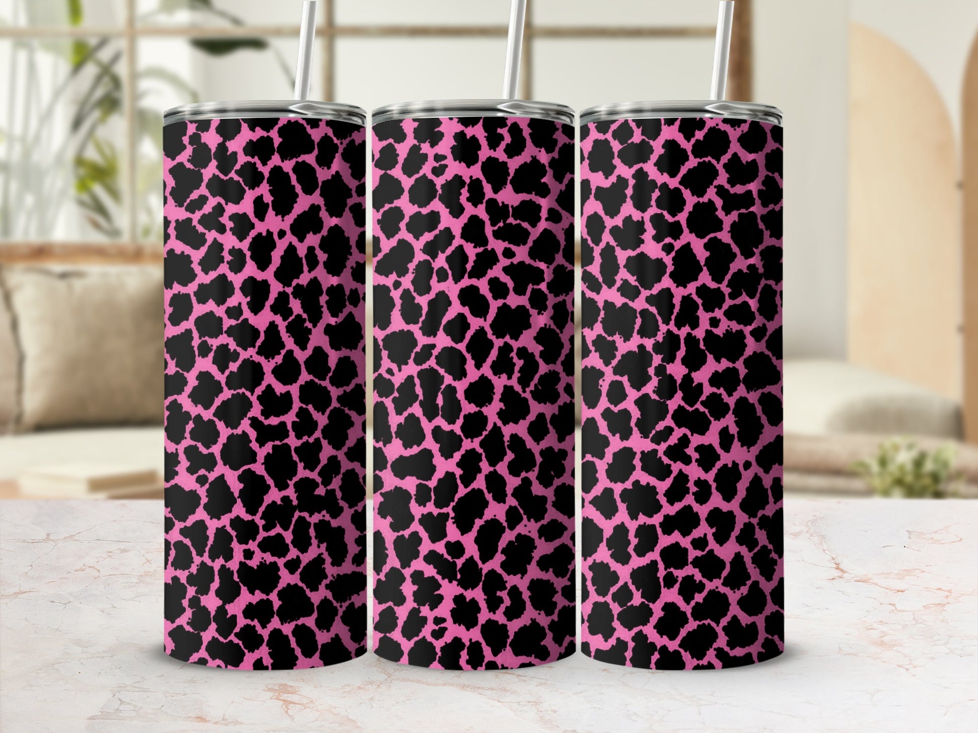 Tumblers with a black and pink animal print pattern and straws.