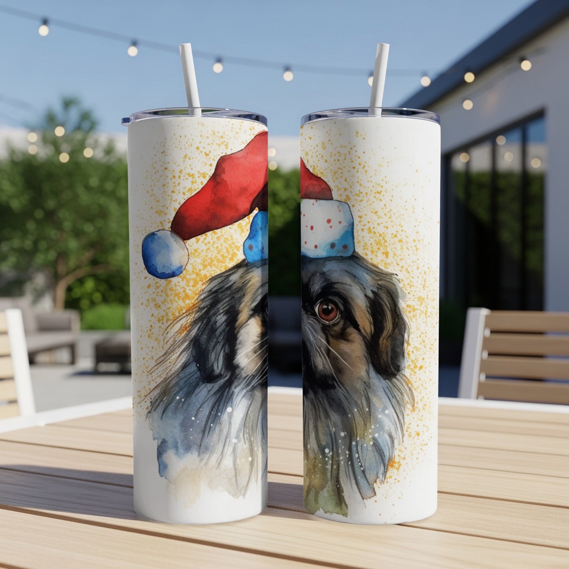 Two tumblers with watercolor dog wearing Santa hat, on outdoor table.