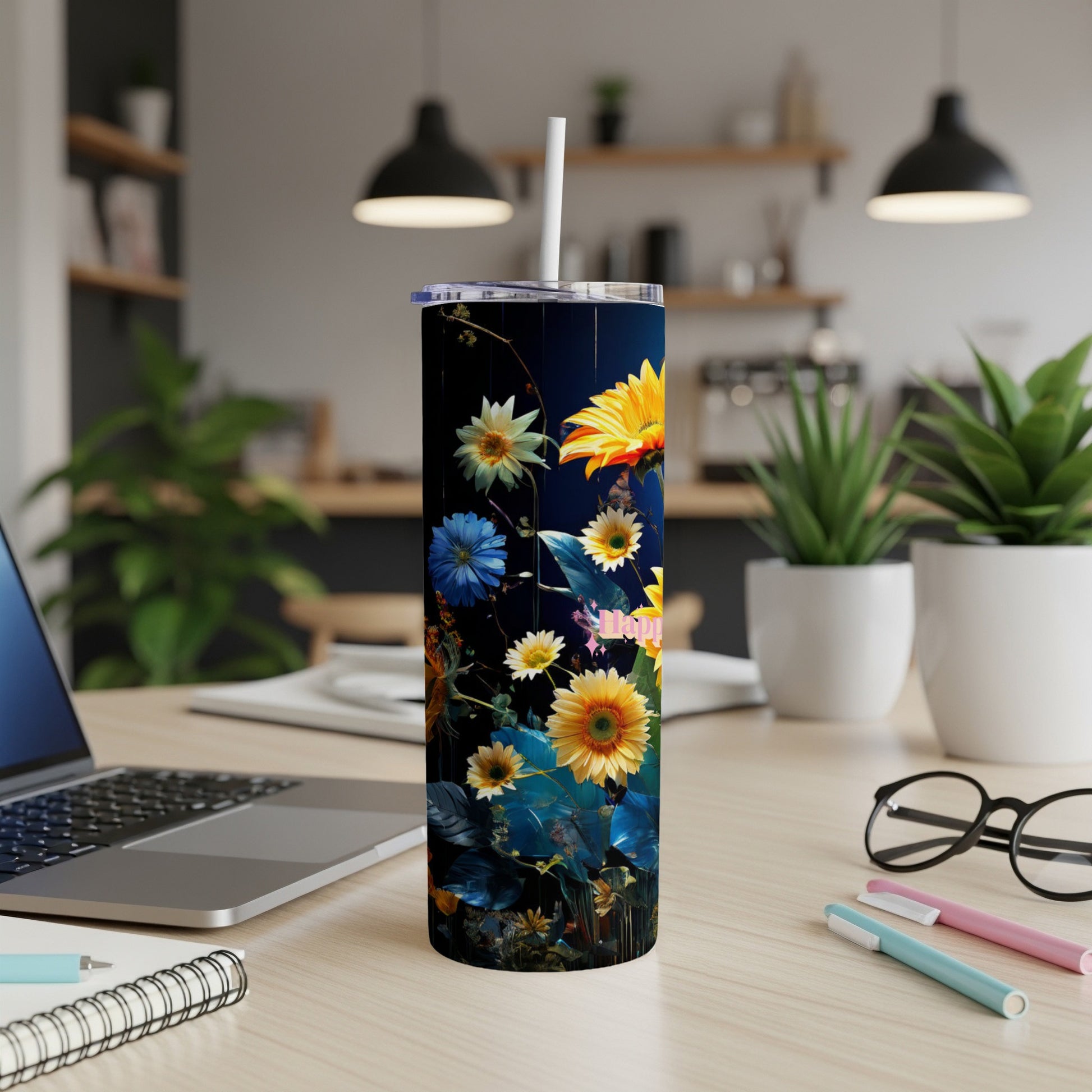 Dark tumbler with vibrant floral design on a desk with laptop and pens.