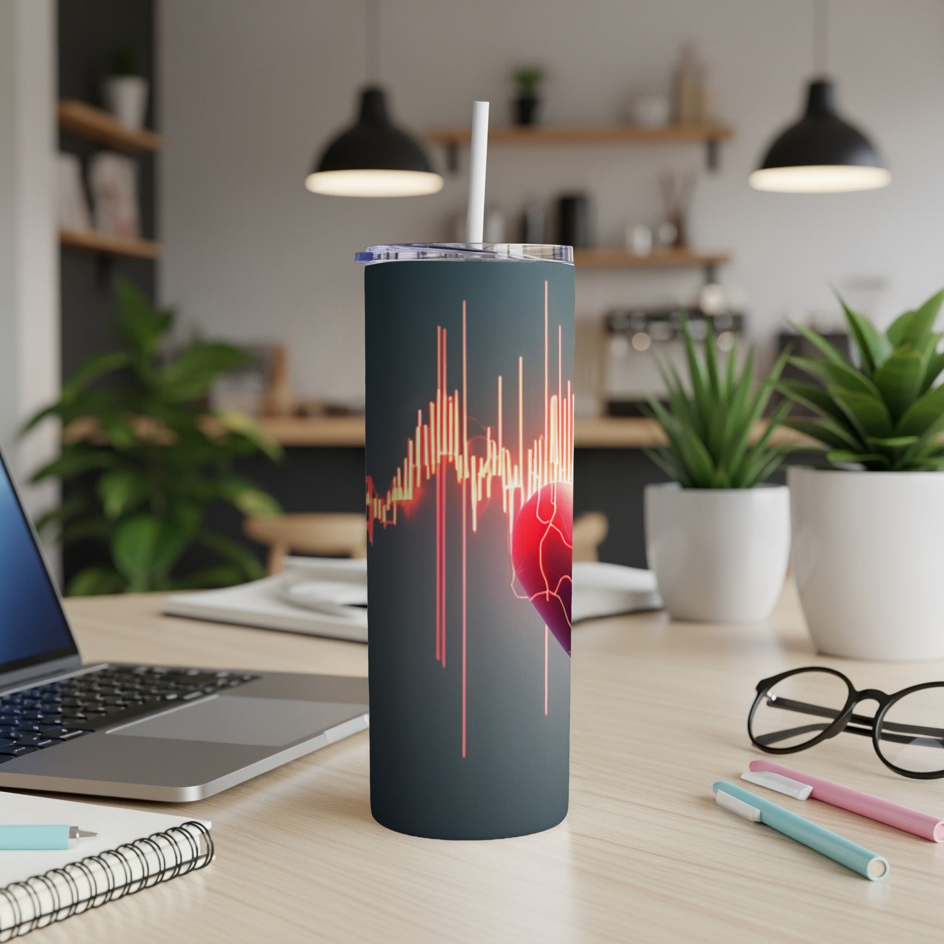 Tumbler with heart and graph overlay, on a desk with laptop and pens.