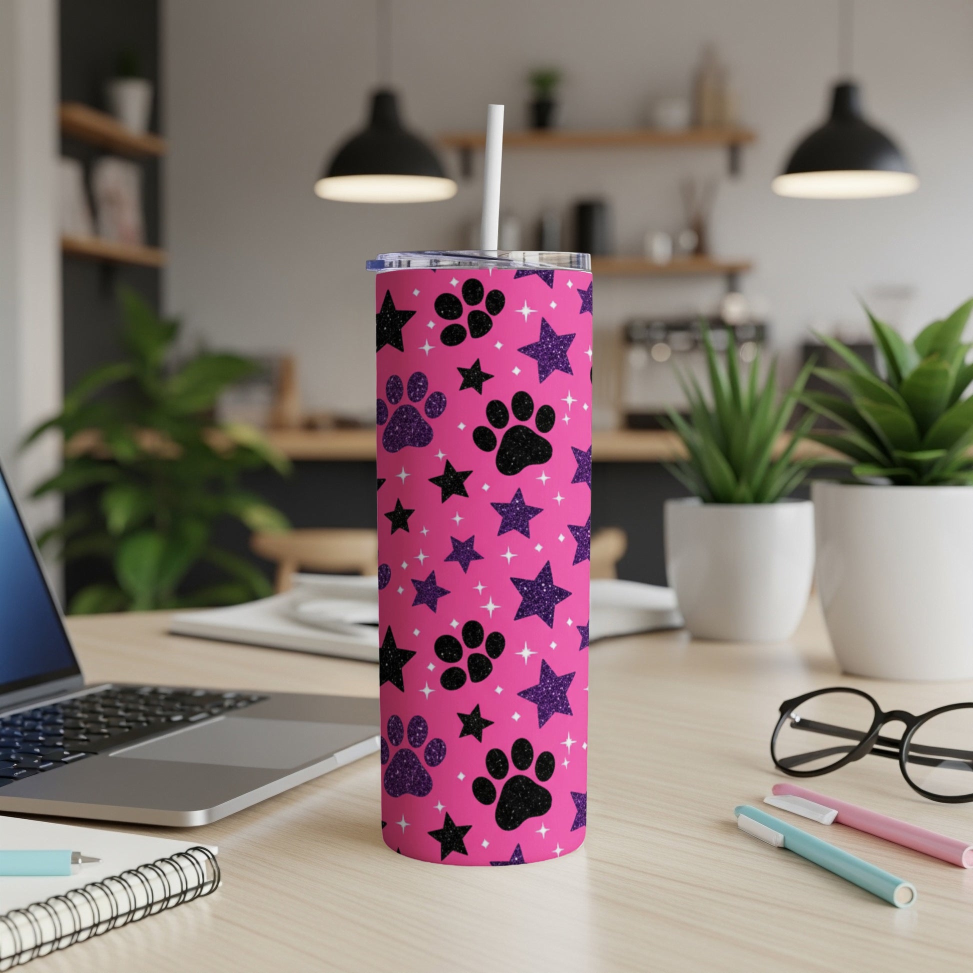 Pink tumbler with black paw prints and glitter stars, with a straw.