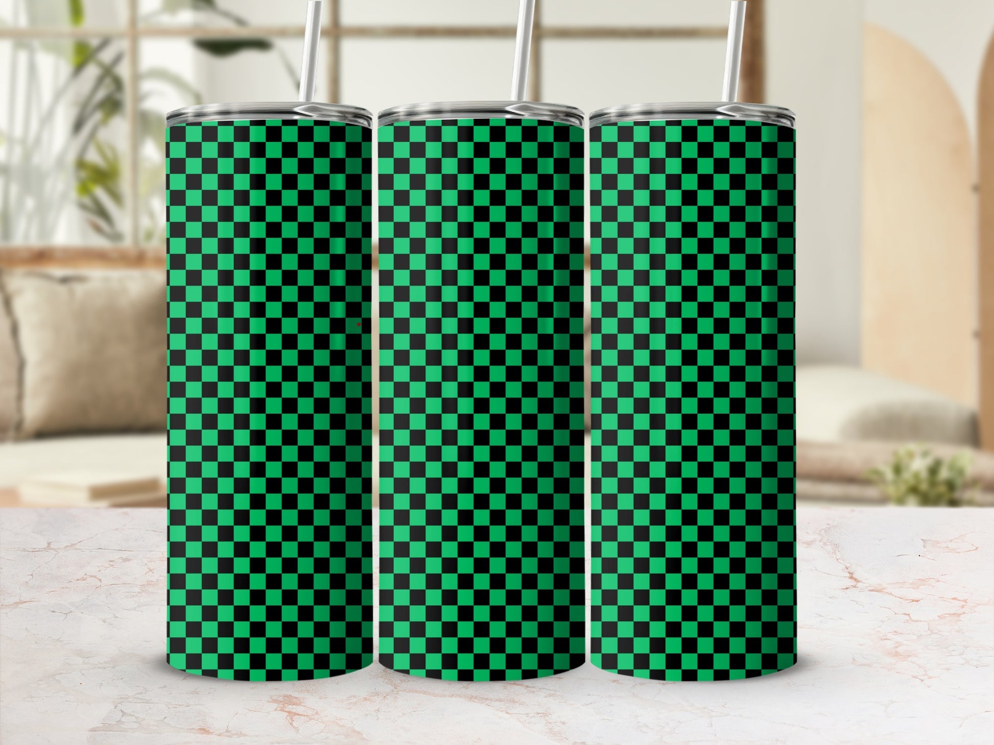 Three green and black checkered tumblers with straws on a marble surface.