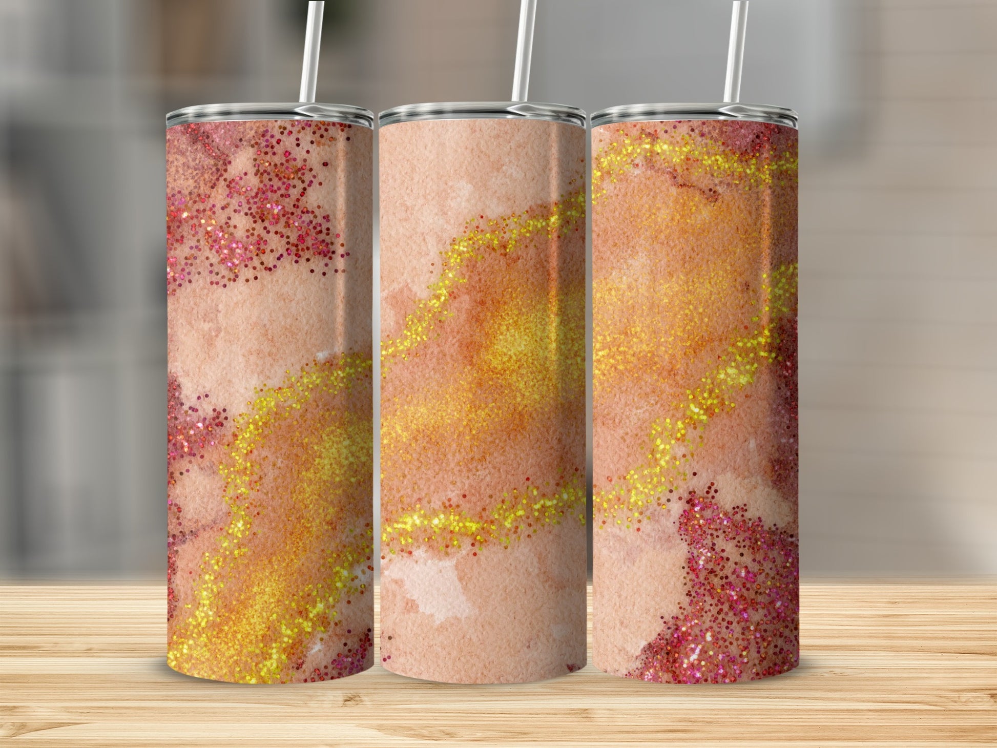 Three tumblers with a watercolor and glitter design in shades of peach and gold.