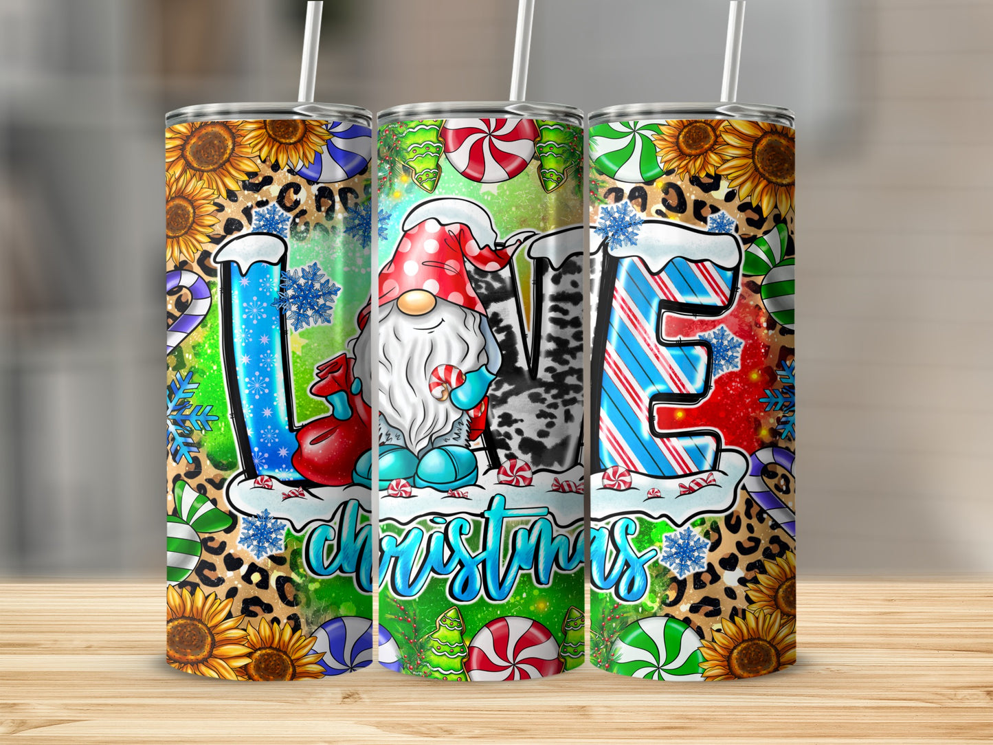 Three tumblers decorated with "LOVE Christmas" text, a gnome, sunflowers, and leopard print.