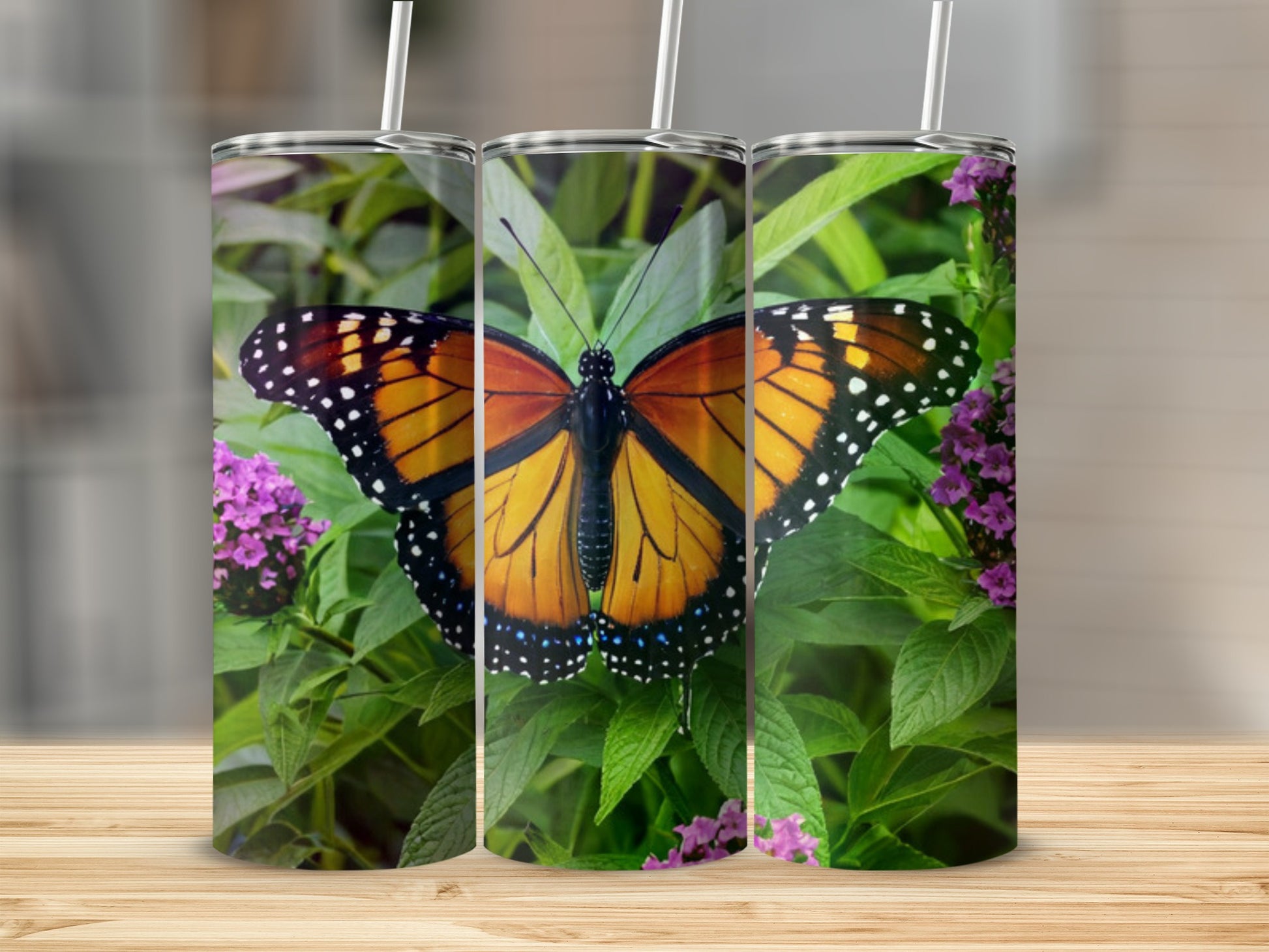 Monarch butterfly on green leaves and purple flowers, printed on three tumblers.