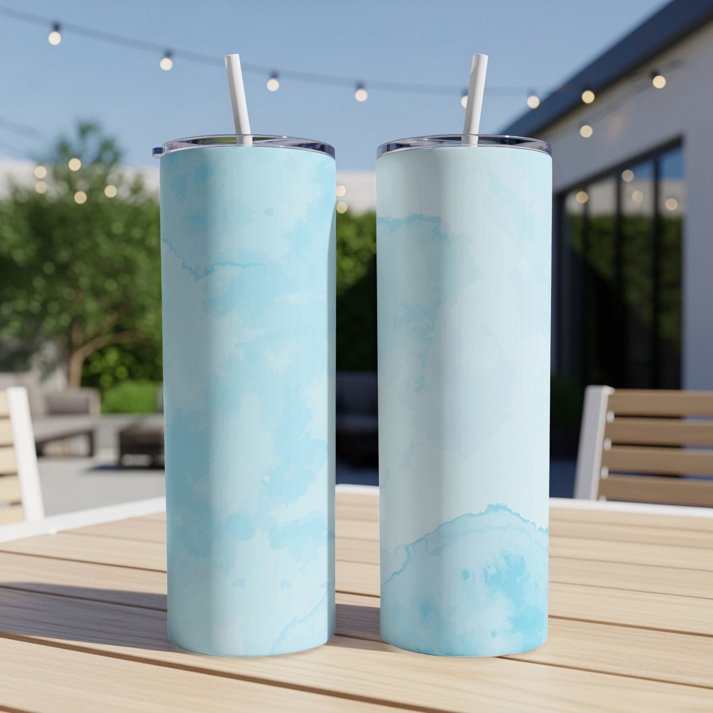 Two blue watercolor pattern tumblers with straws sit on a wooden table.