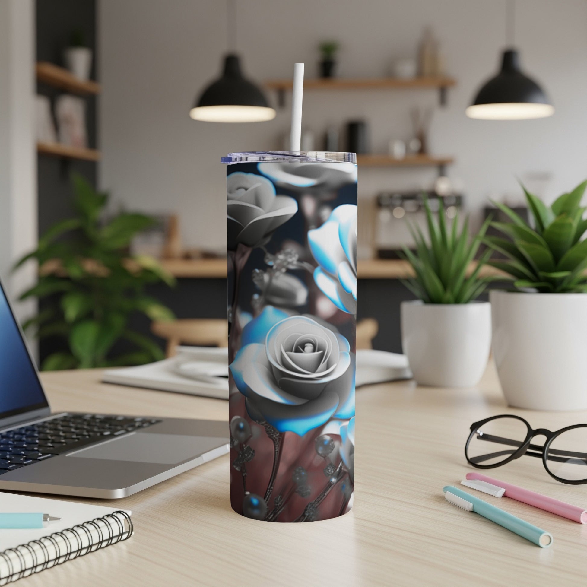 Silver and blue floral tumbler with straw on a desk.