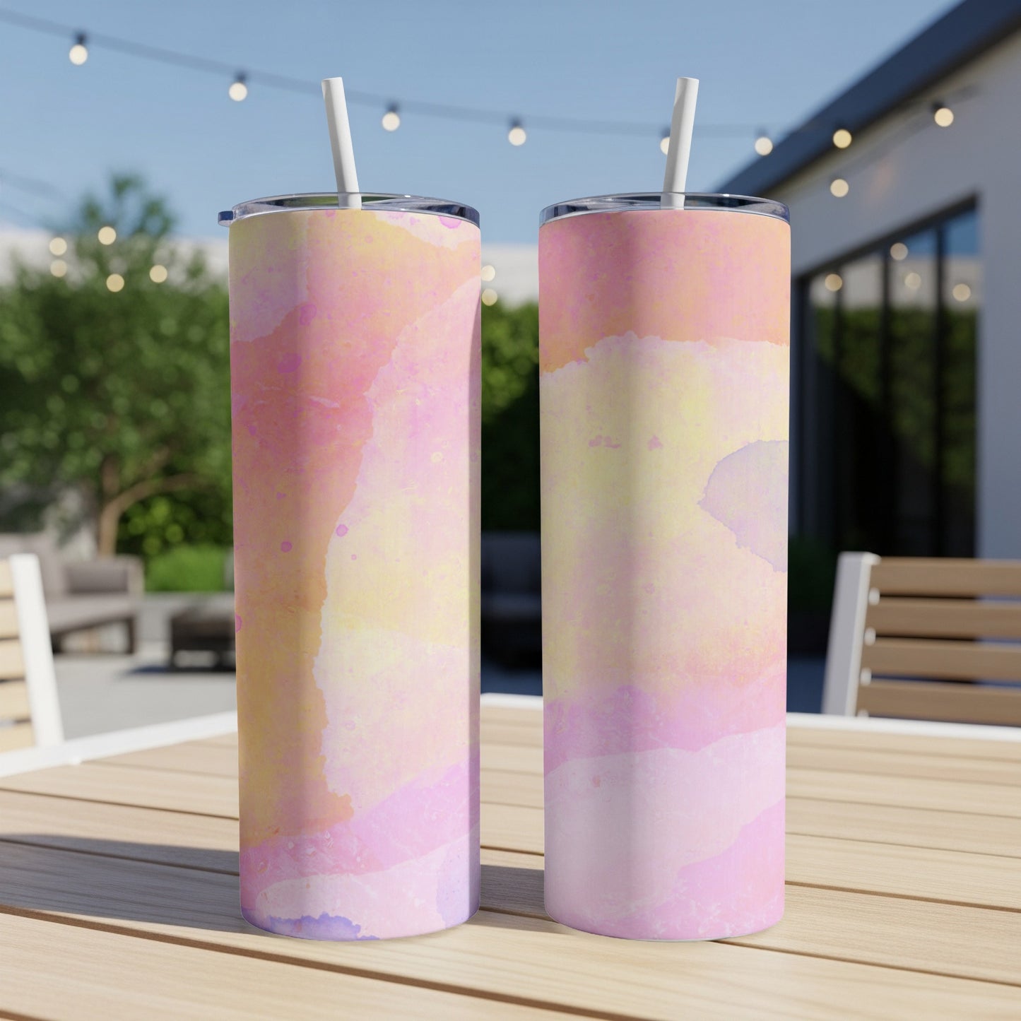 Two tumblers with a pink and yellow watercolor pattern sit on a wooden table.