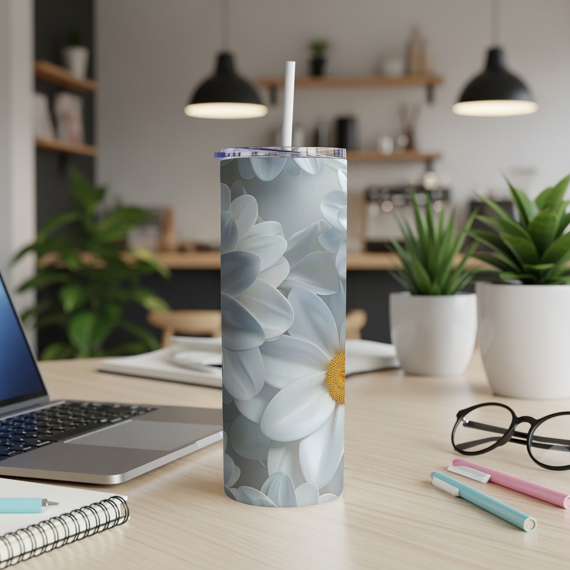 White and yellow daisy pattern on a silver tumbler with a straw.