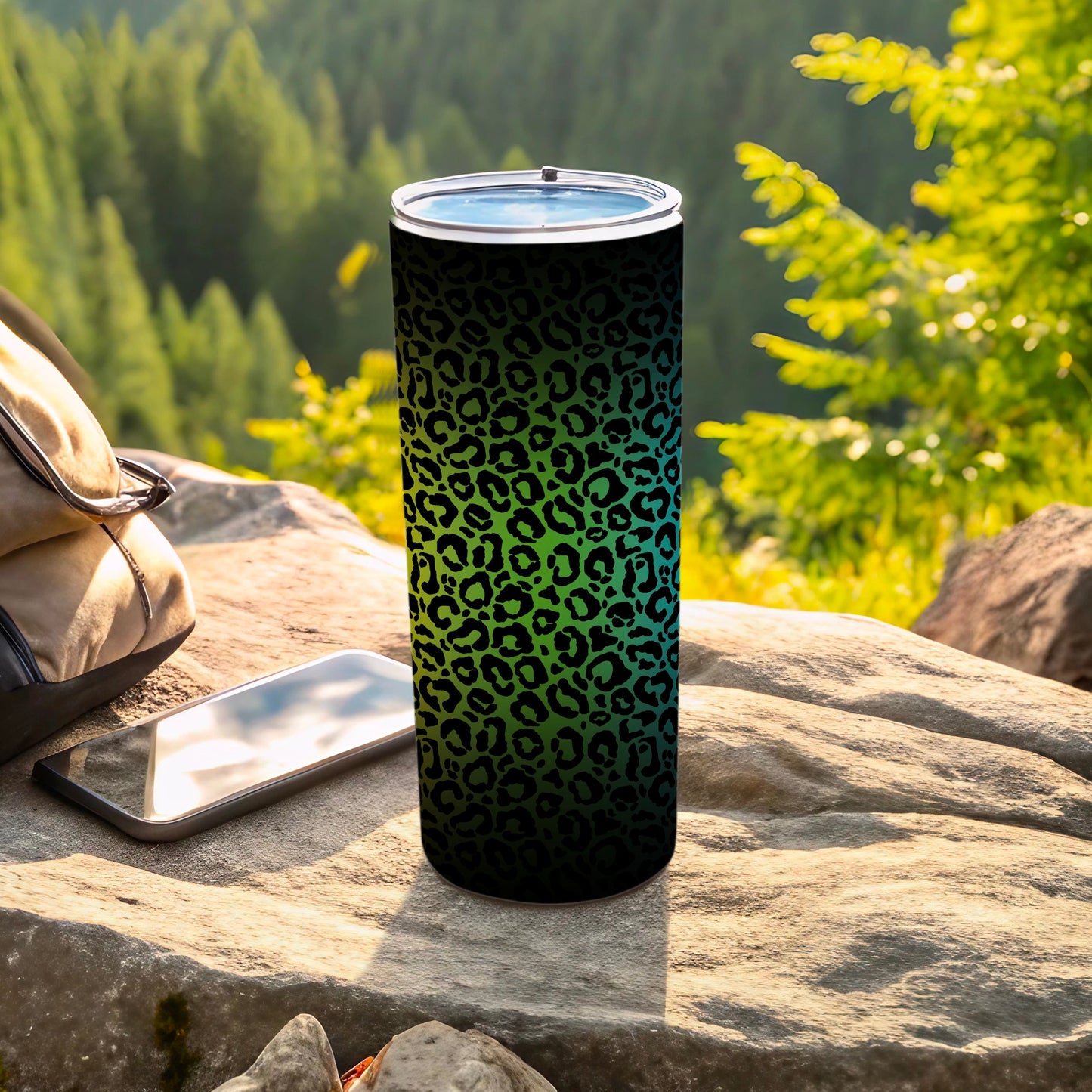 Black and green leopard print tumbler with a phone and backpack outdoors.