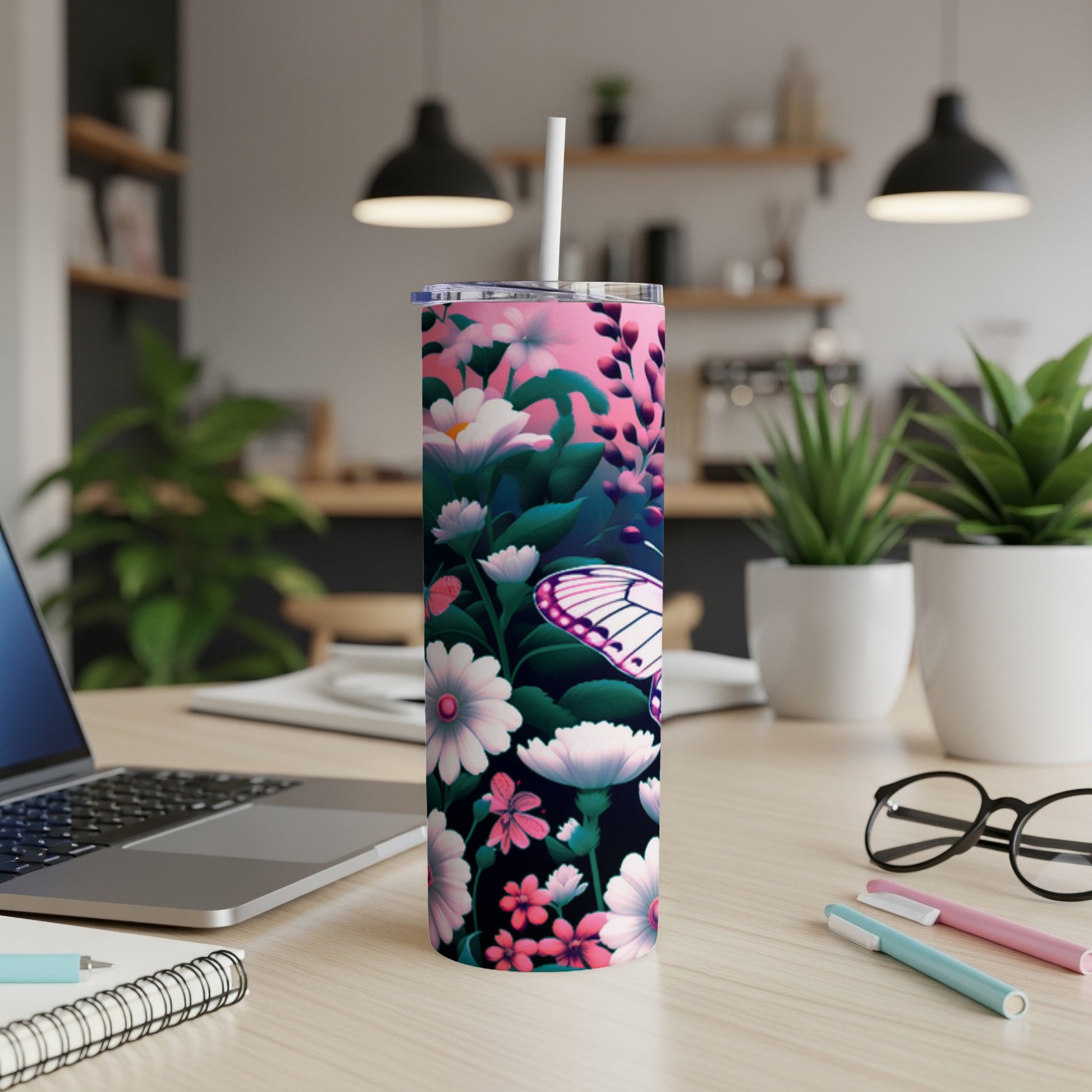 Pink floral tumbler with butterfly, on a desk with laptop and pens.