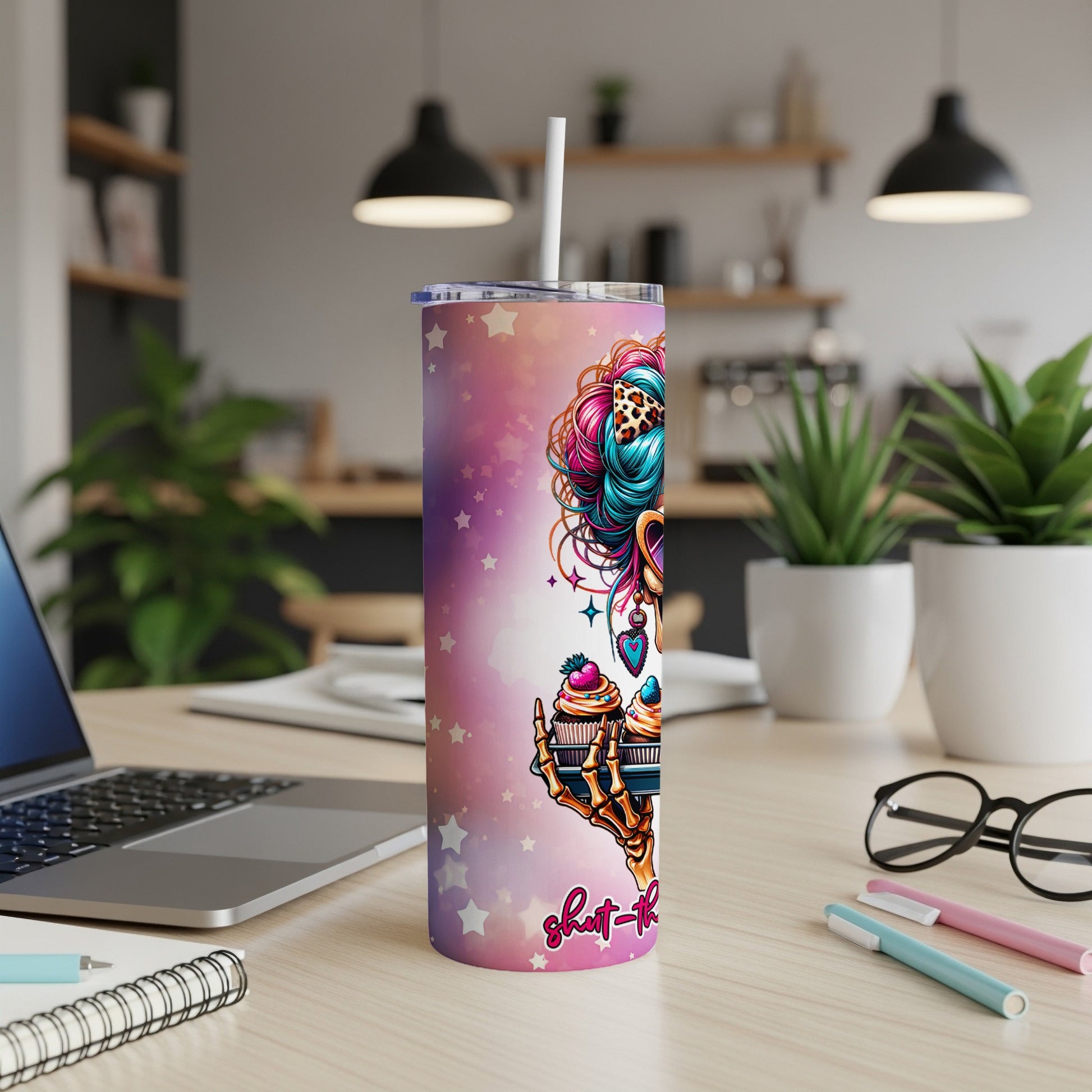 Tumbler with colorful cupcake art and skull graphic, on a desk.
