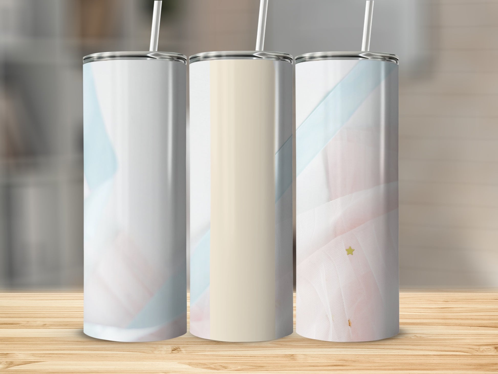 Three tumblers with abstract pastel designs and a light wood background.
