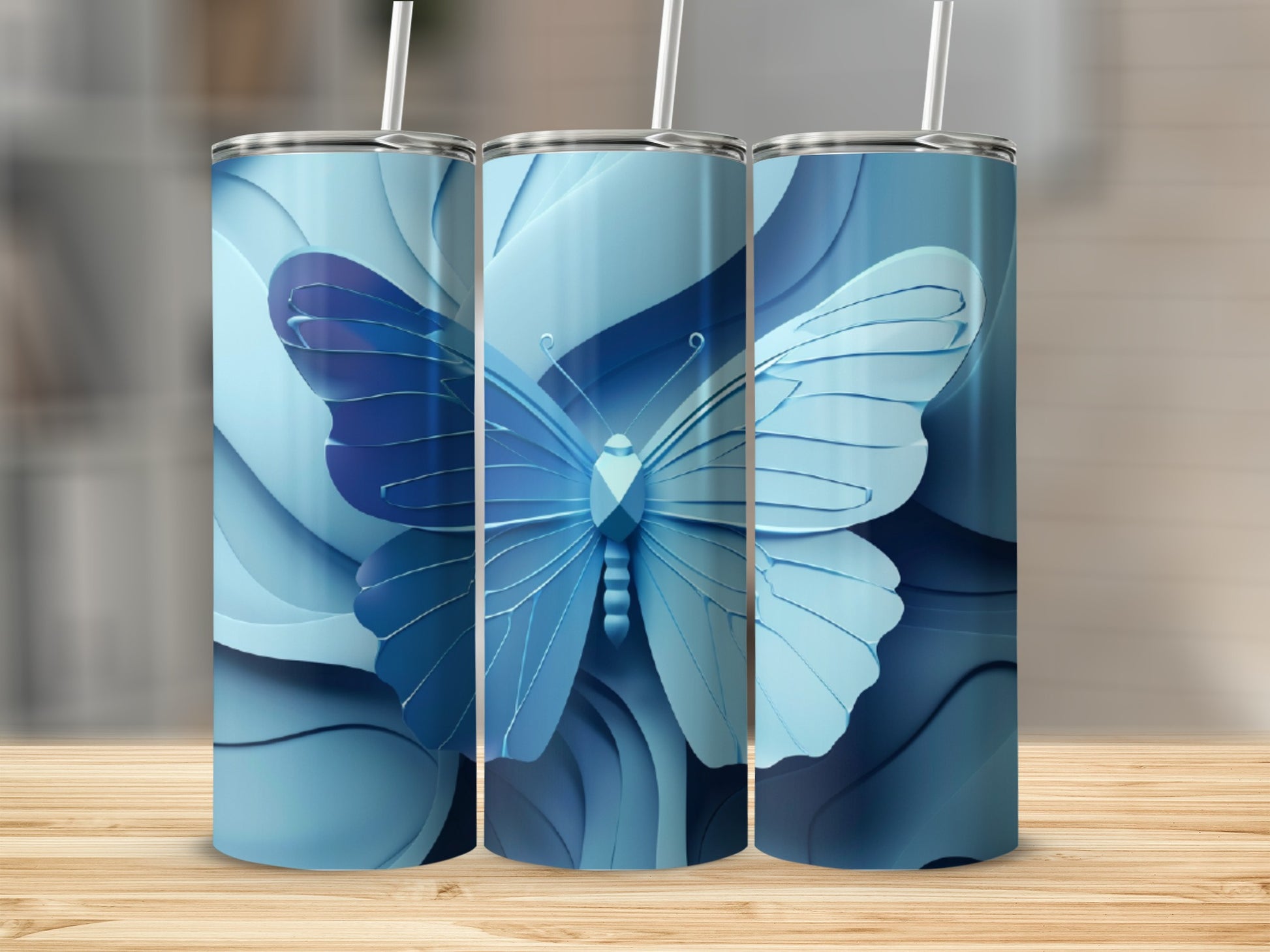 Three blue tumblers with butterfly and layered floral designs.