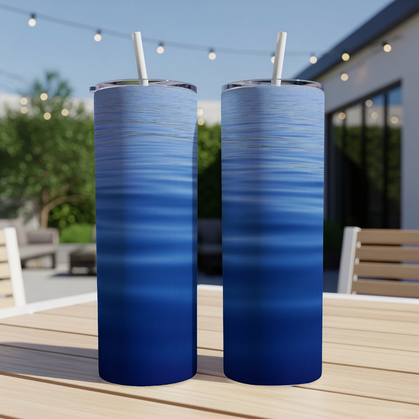 Two blue ombre tumblers with straws sit on a wooden table.