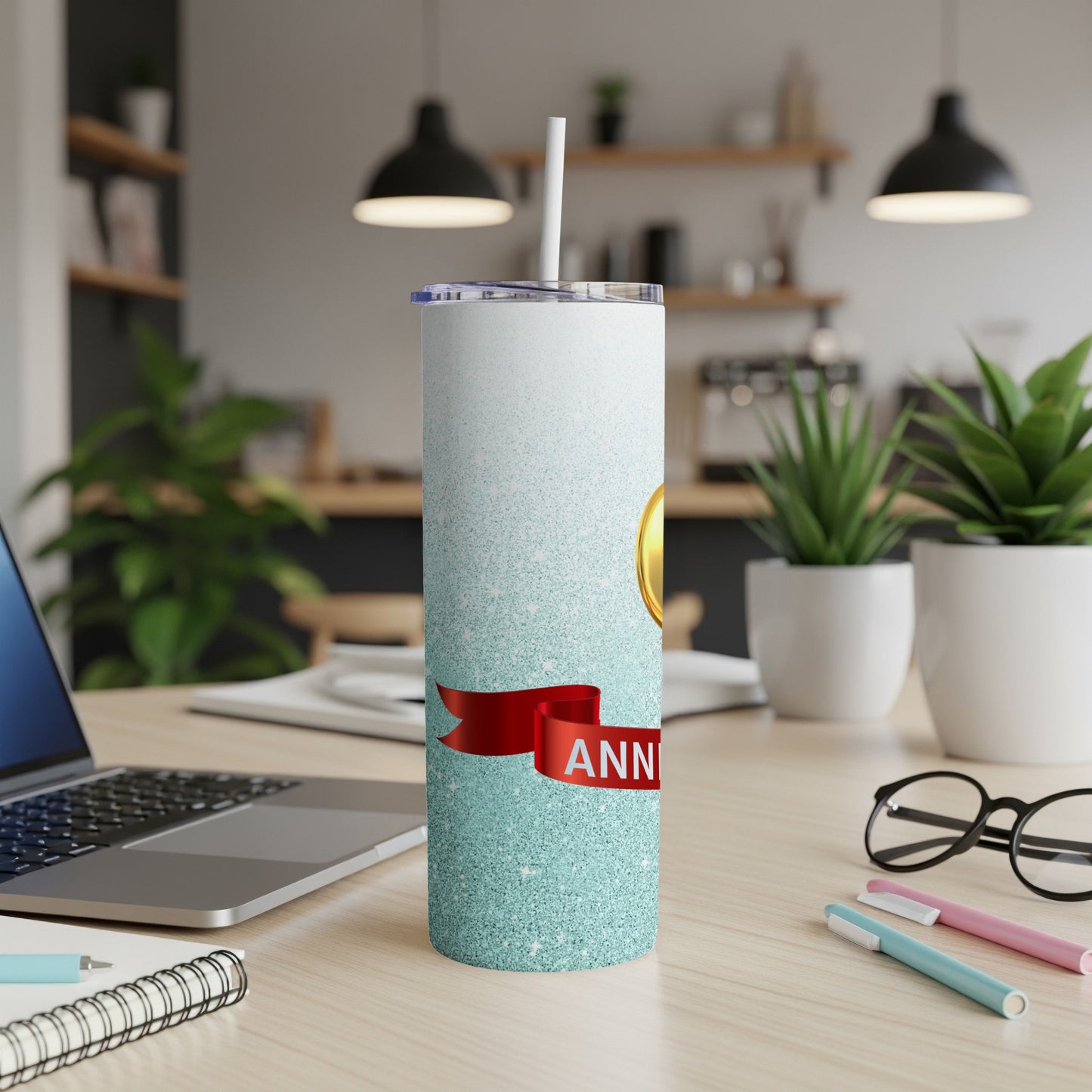 Glittery tumbler with a red ribbon and "ANNIVERSARY" text, on a desk.