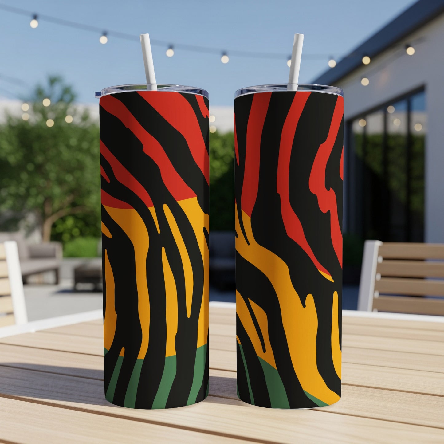 Two tumblers with red, yellow, green, and black stripe pattern sit on a wooden table.