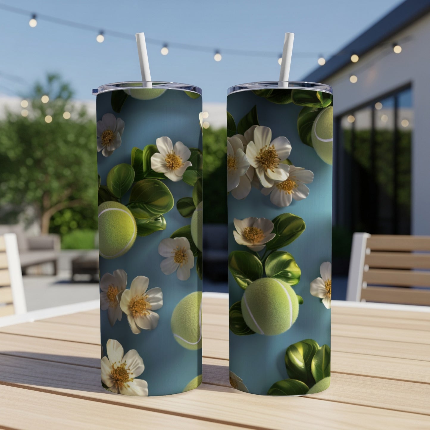 Two tall tumblers with tennis balls and white flowers on a wooden table.