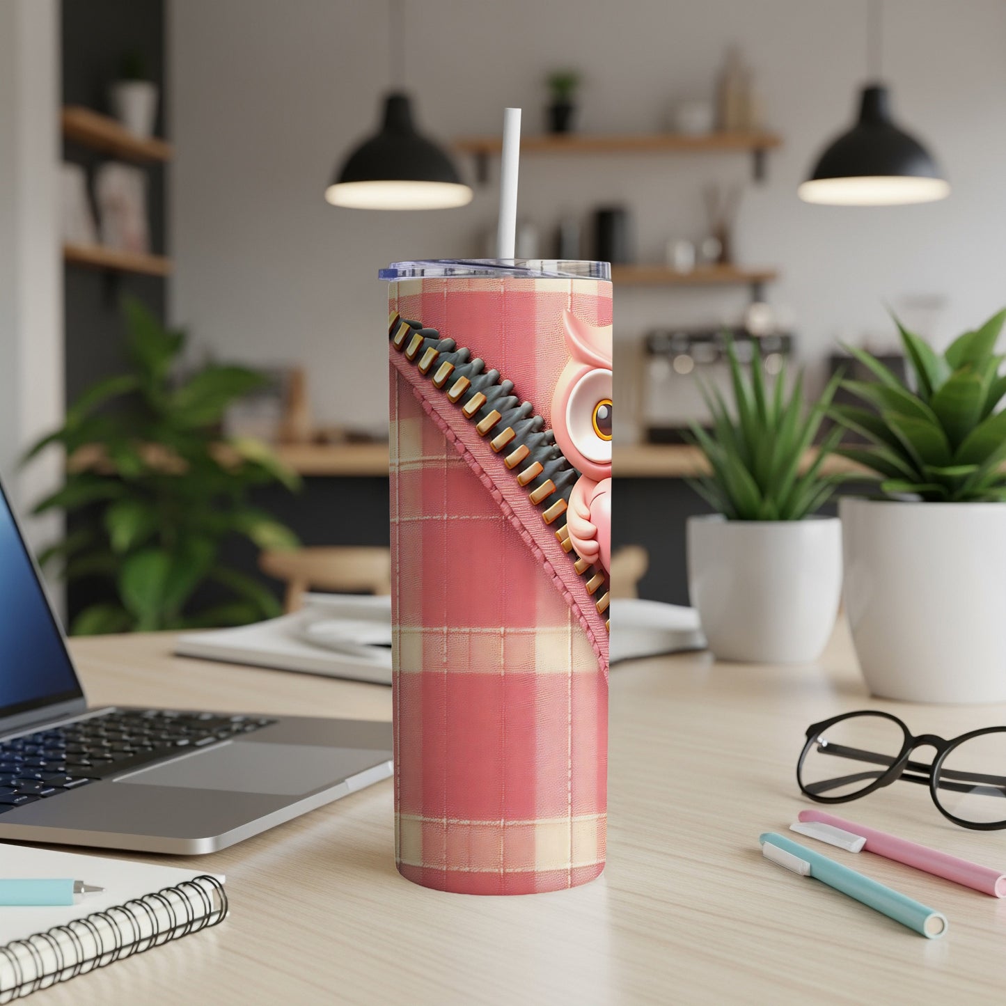Pink owl tumbler with plaid design and straw on a desk.