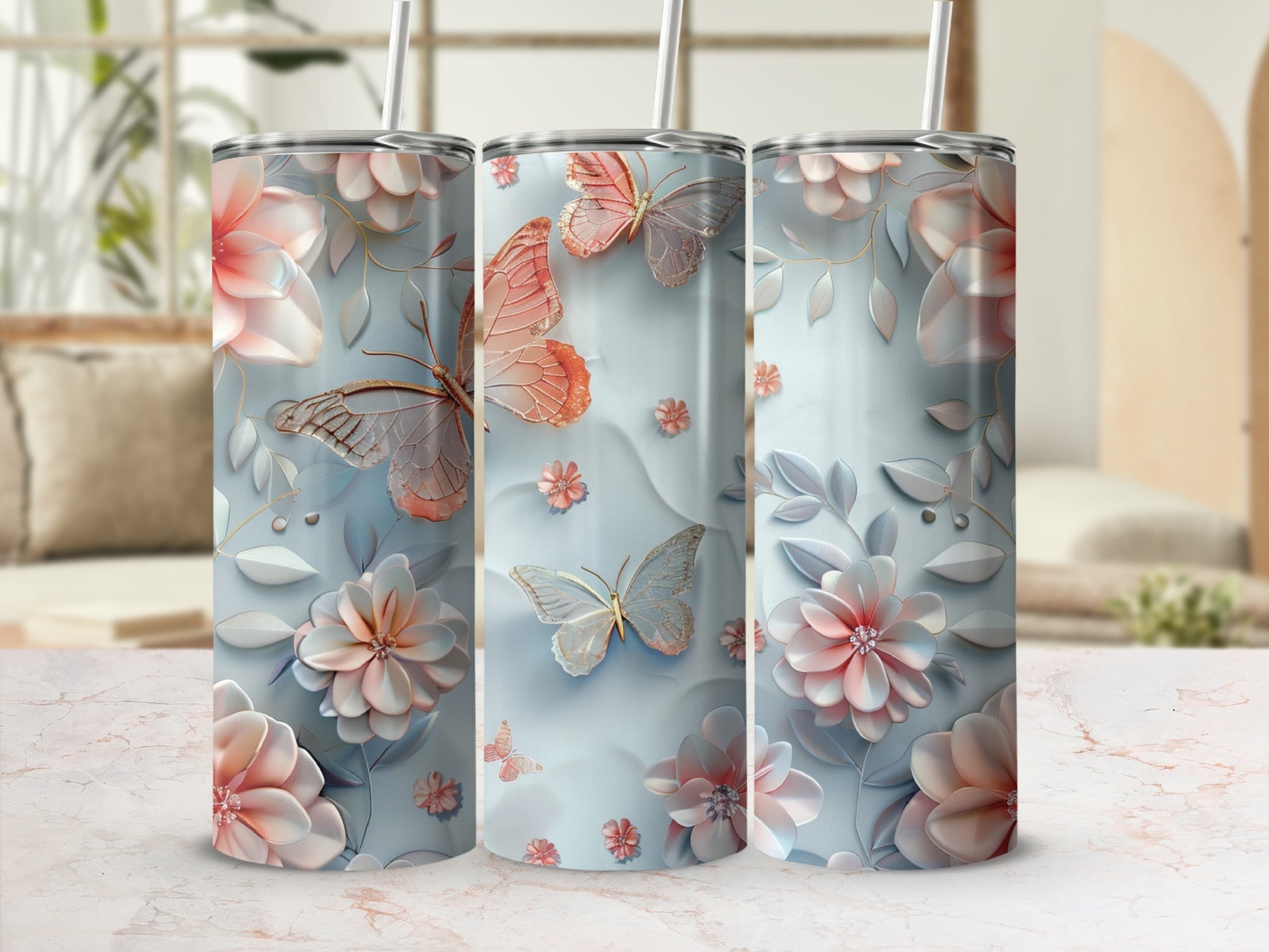 Floral and butterfly design on three silver tumblers with straws.