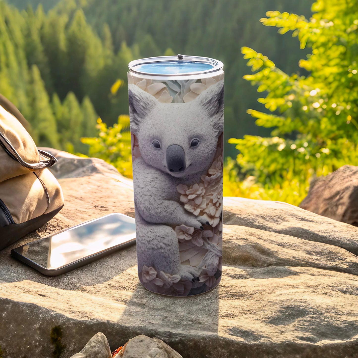 Tumbler with a floral koala design resting on a rock outdoors.