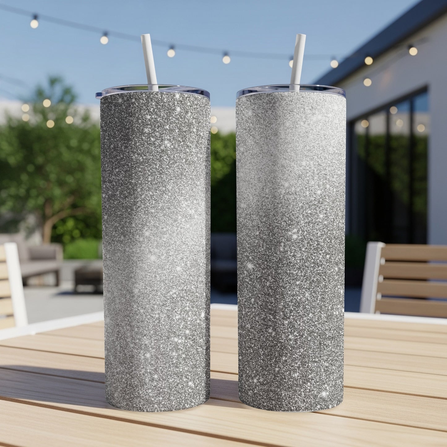 Two tall tumblers with a gradient silver glitter design and white straws.