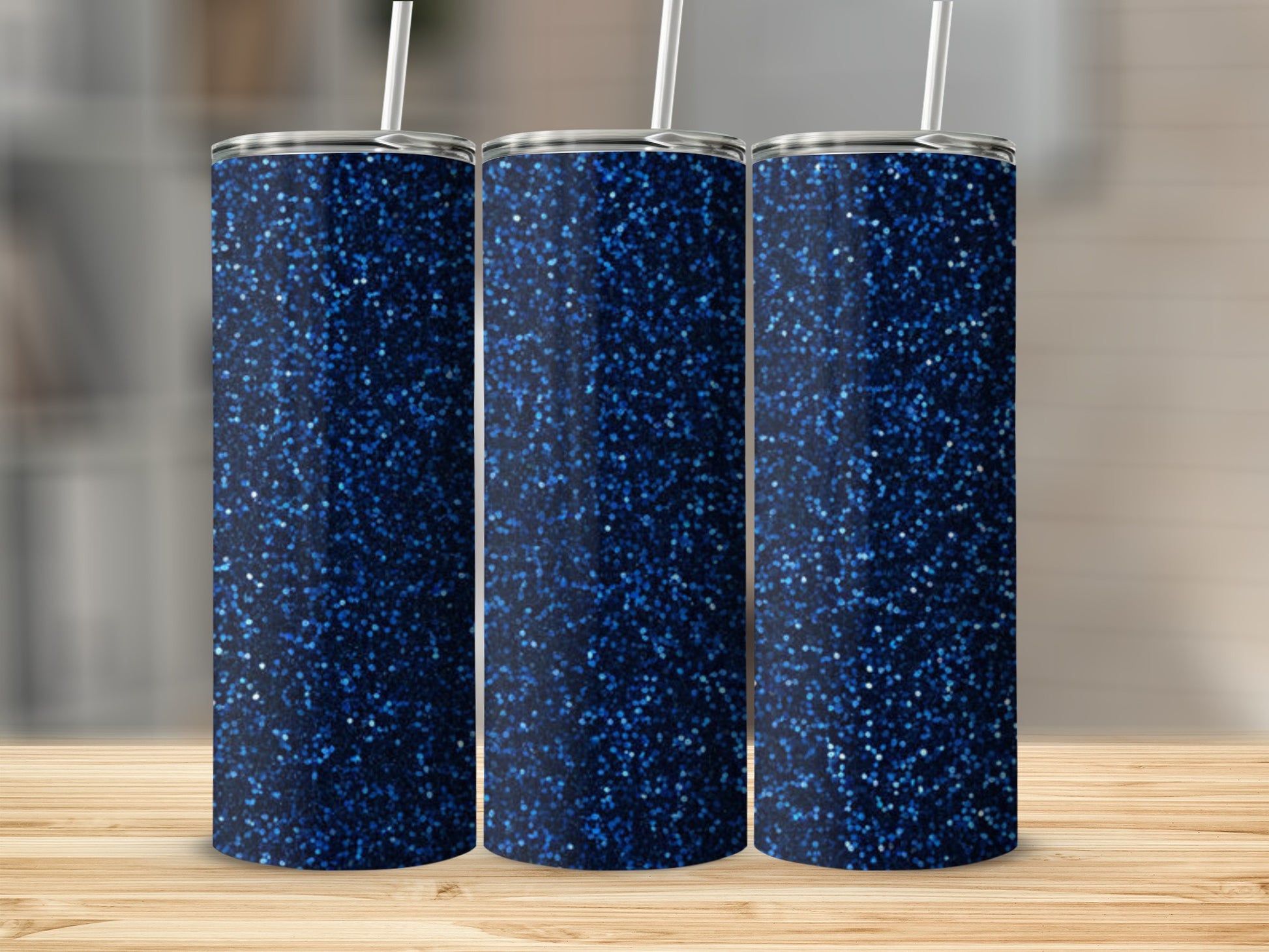 Three navy blue glitter tumblers with white straws on a wooden surface.