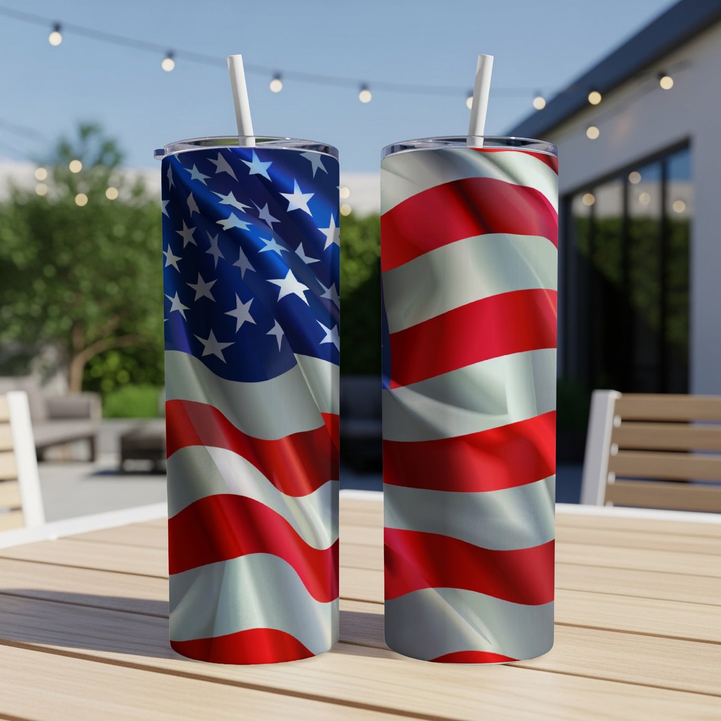 Two American flag tumblers with straws on a wooden table outdoors.