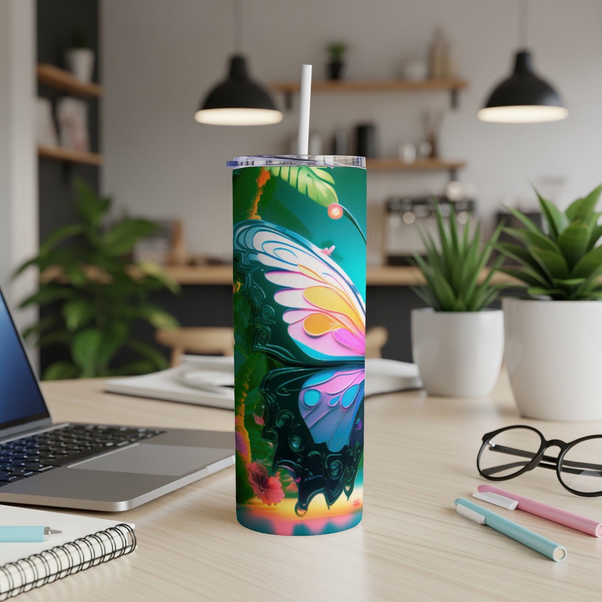 Butterfly tumbler with colorful wings on a desk with a laptop and pens.