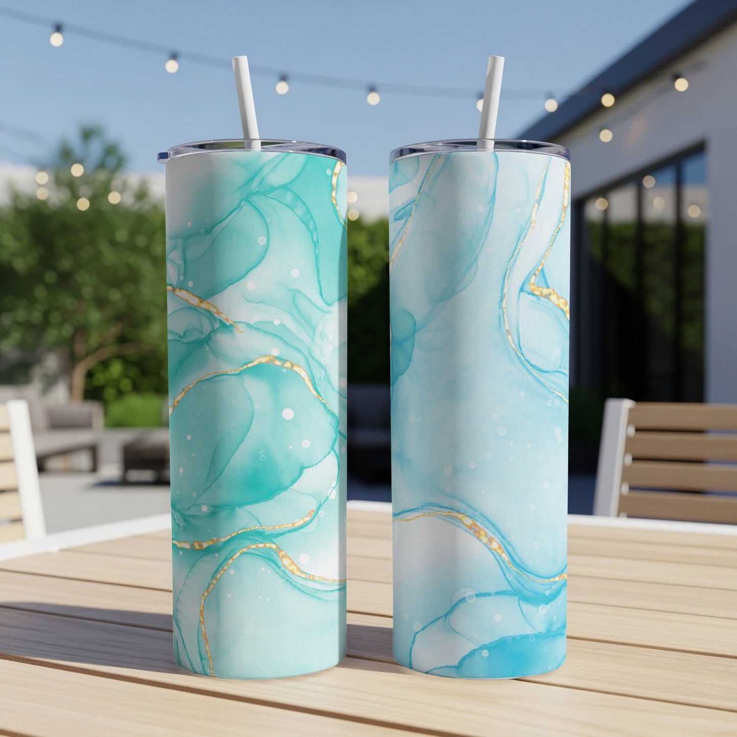 Two tall tumblers with turquoise and gold marbled design on a table.