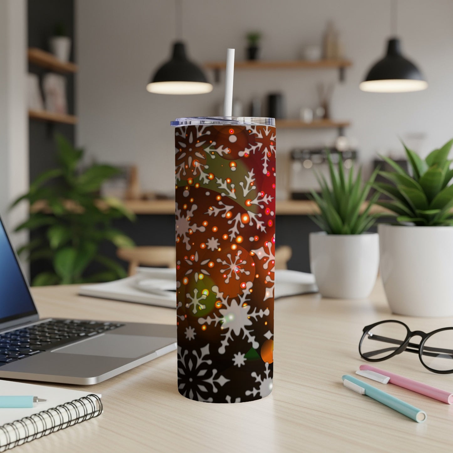 Festive snowflake tumbler with bokeh lights on a desk.
