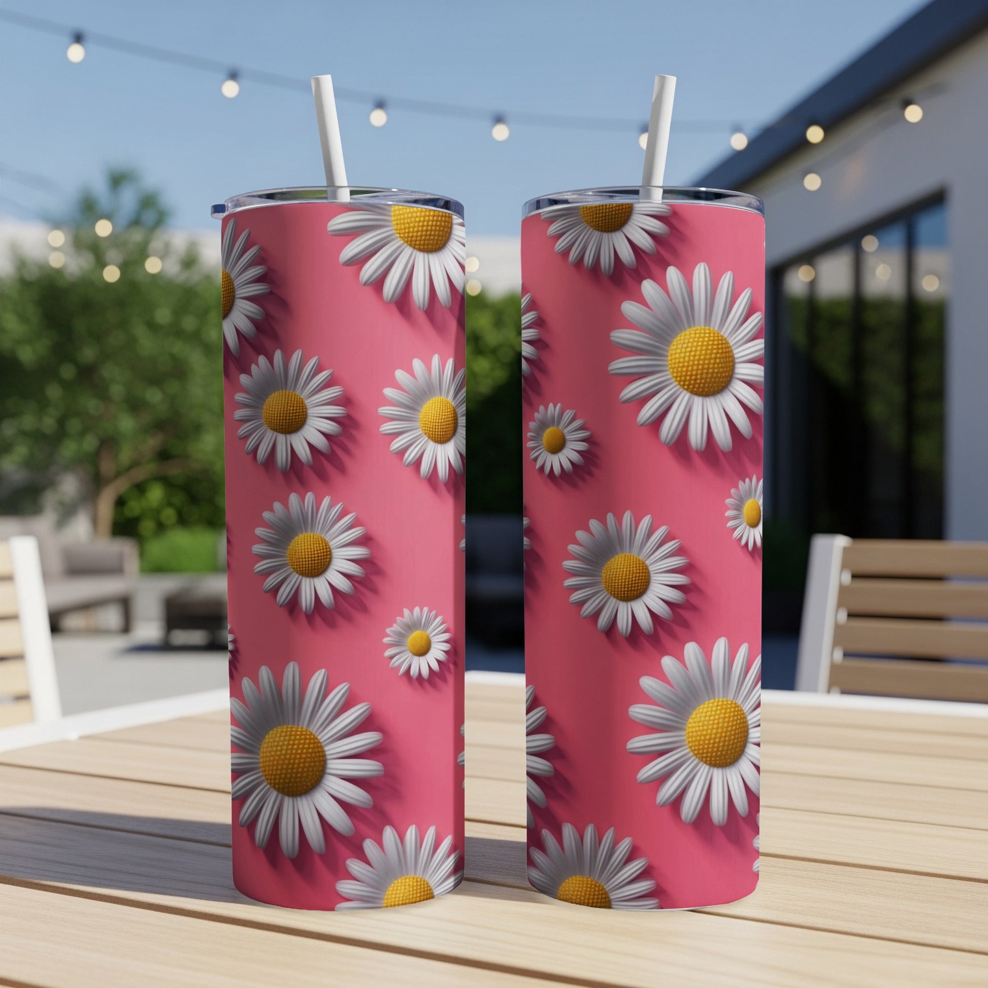 Two pink tumblers with white daisy pattern on a wooden table.