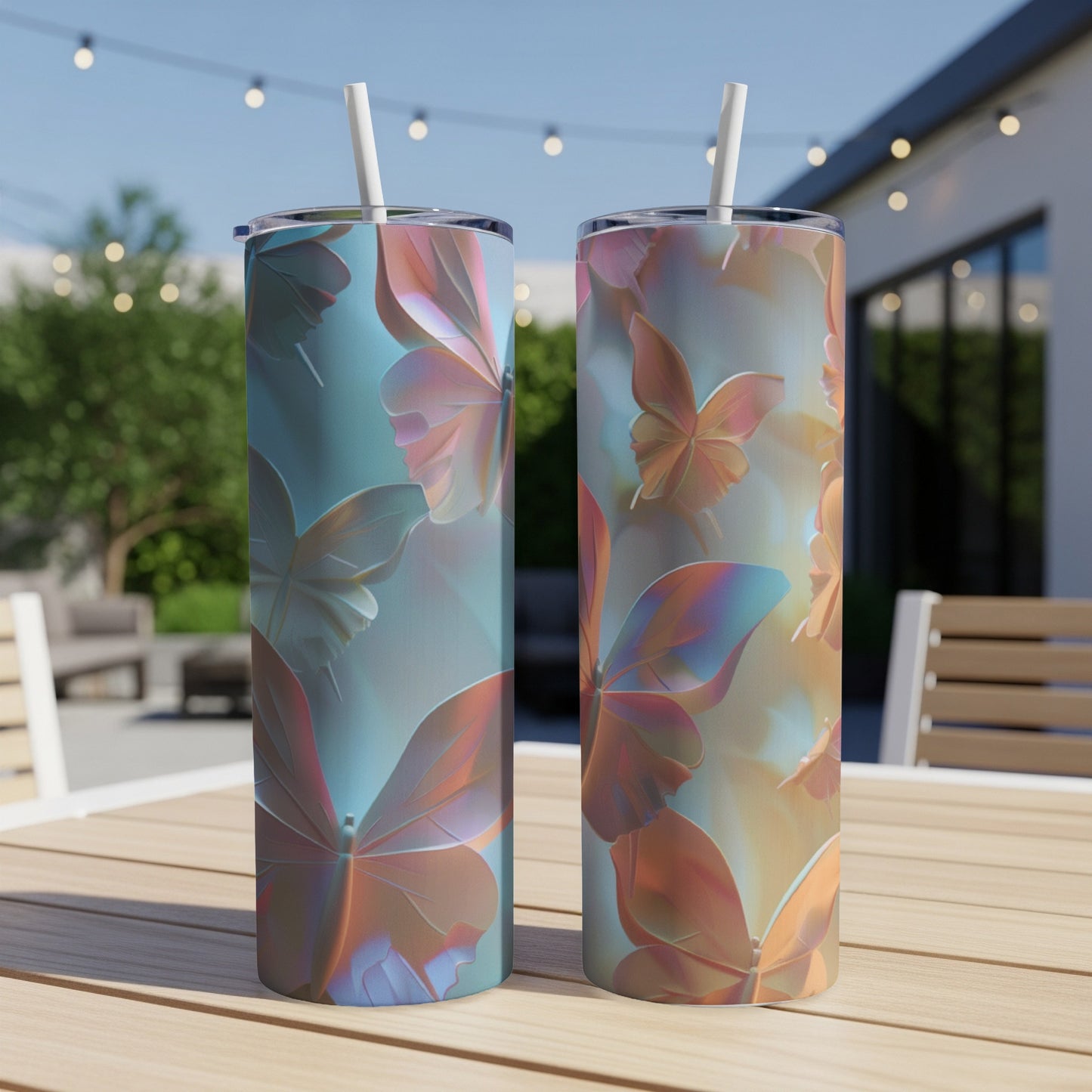 Two iridescent butterfly tumblers with straws on a wooden table outdoors.