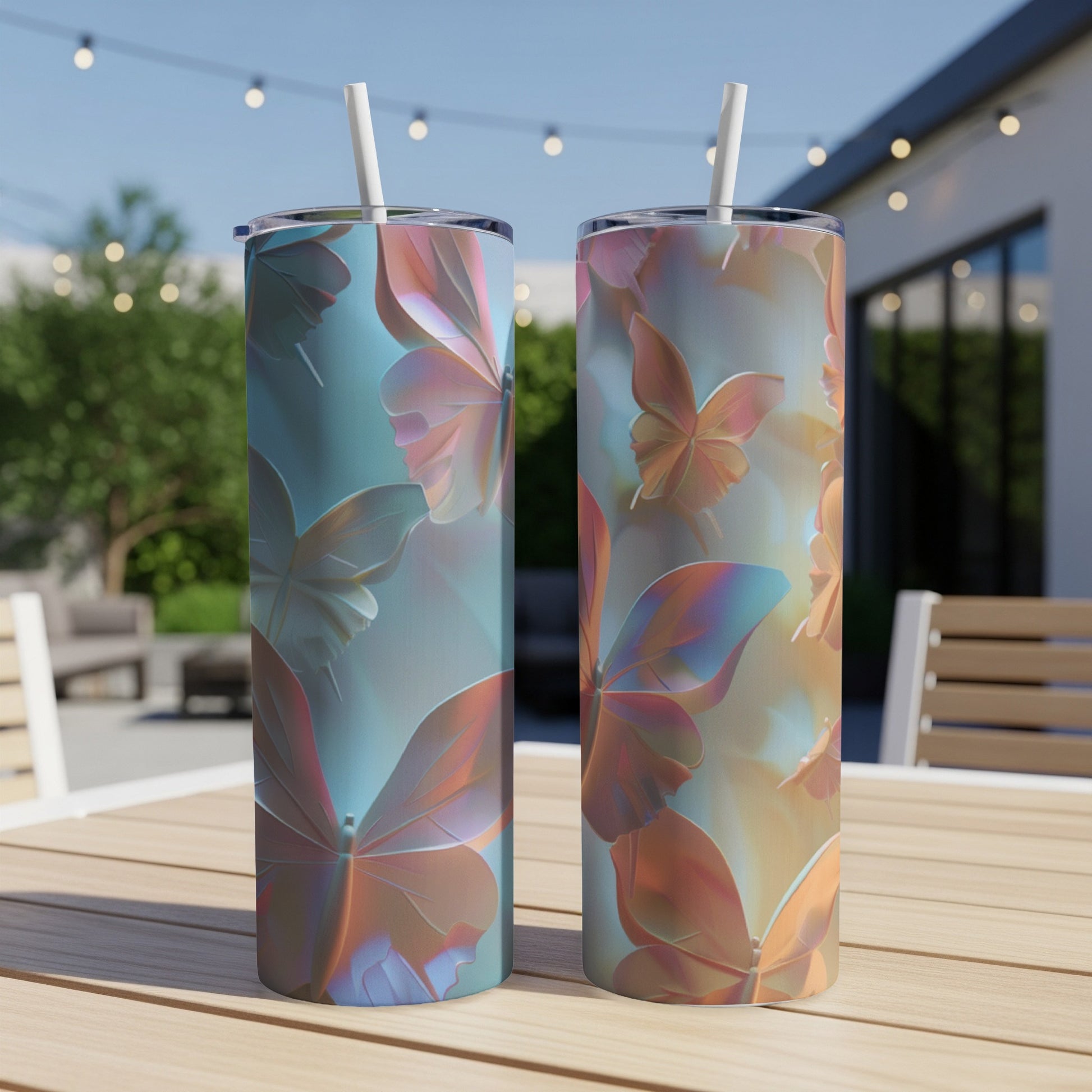 Two iridescent butterfly tumblers with straws on a wooden table outdoors.