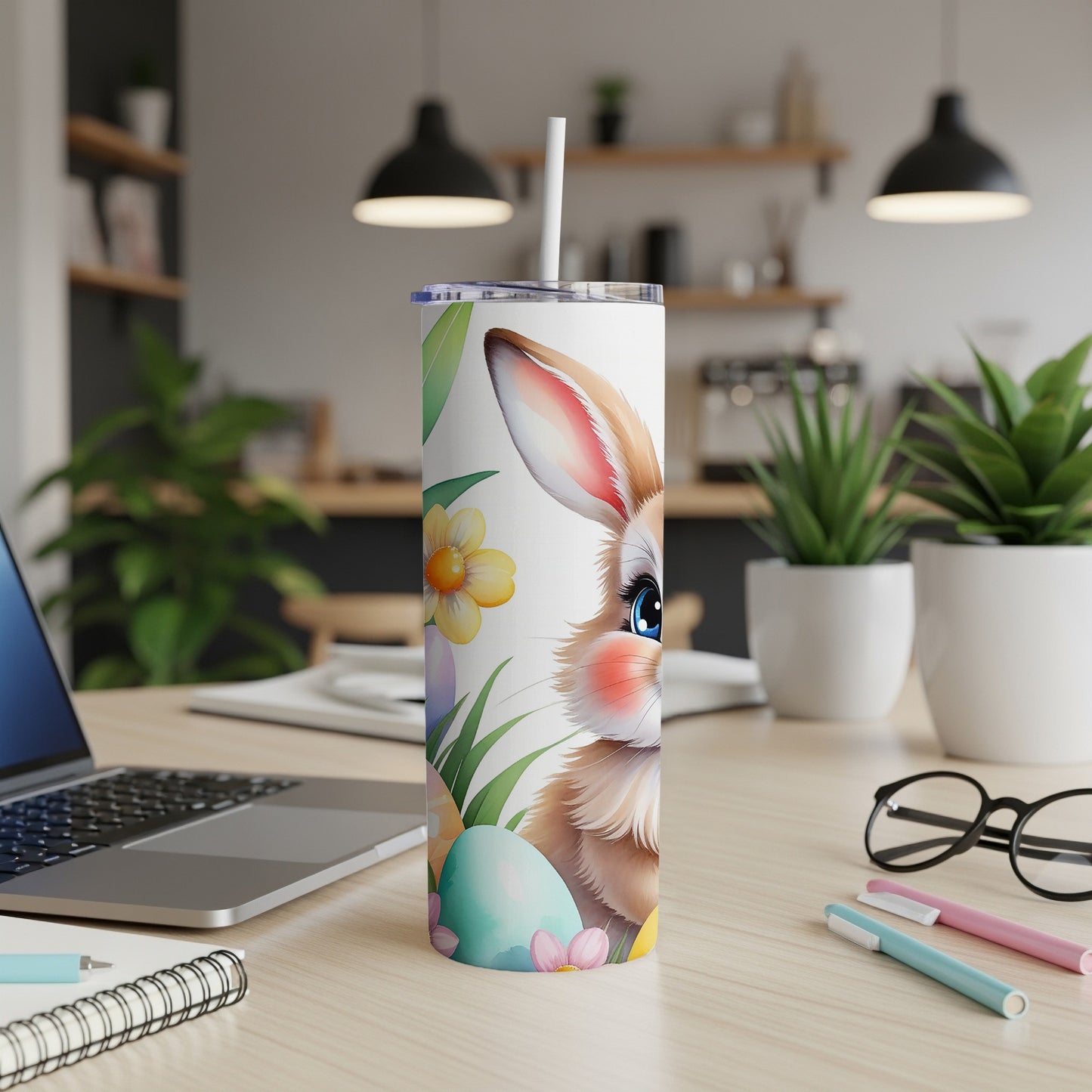 Easter bunny tumbler with flowers and eggs, on a desk with laptop.